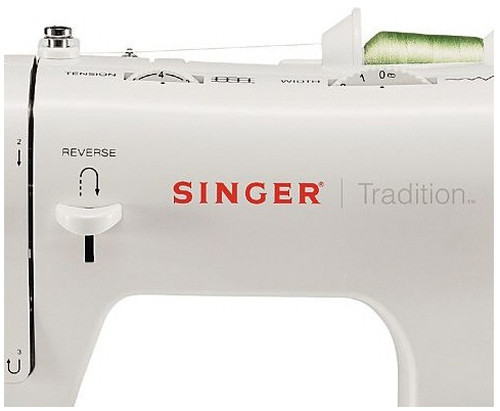 Primer plano de una máquina de coser blanca Singer Tradition con diales e hilo.