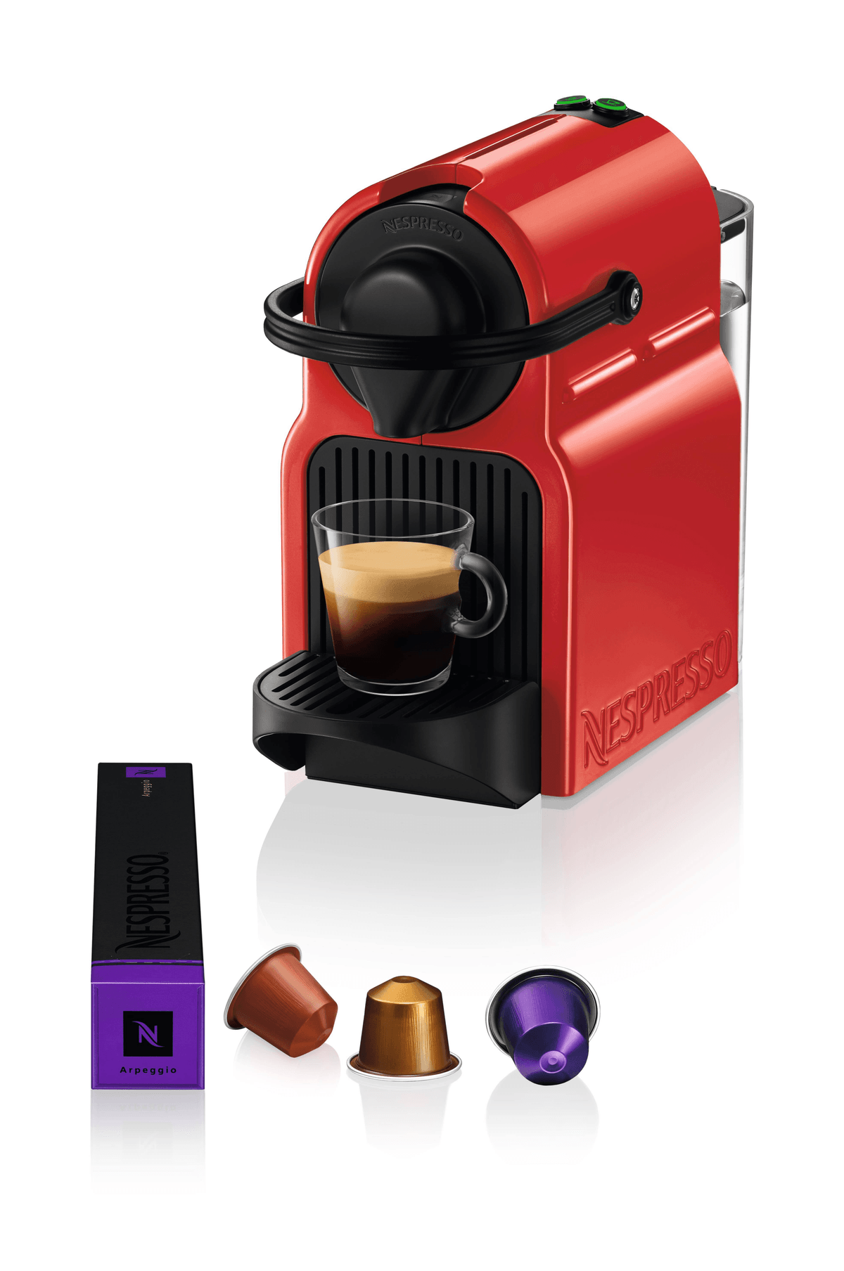 Czerwony ekspres do kawy Nespresso ze szklanką, pudełkiem i trzema kapsułkami.