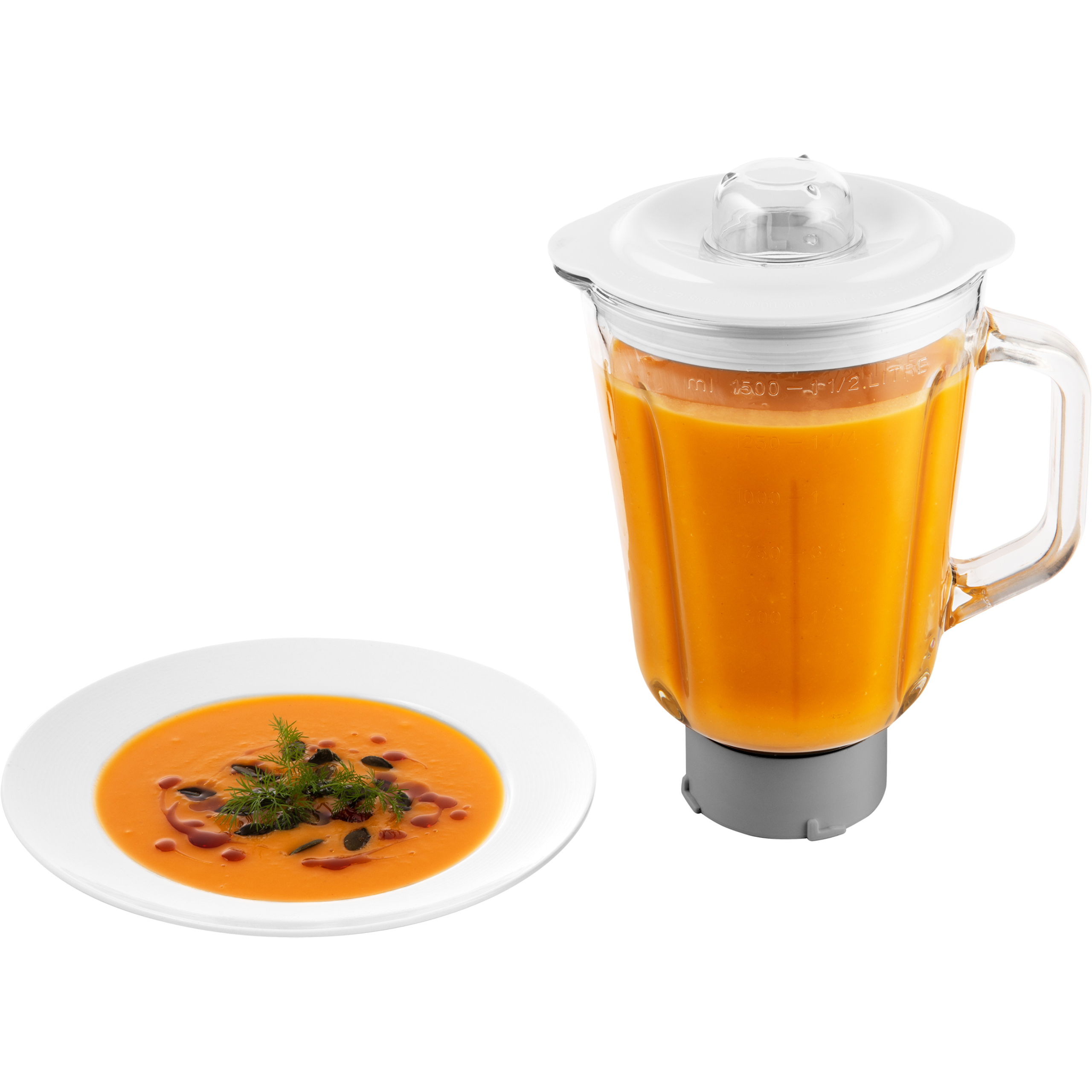 Un piatto bianco di zuppa arancione con erbe accanto a un frullatore in vetro pieno di zuppa.