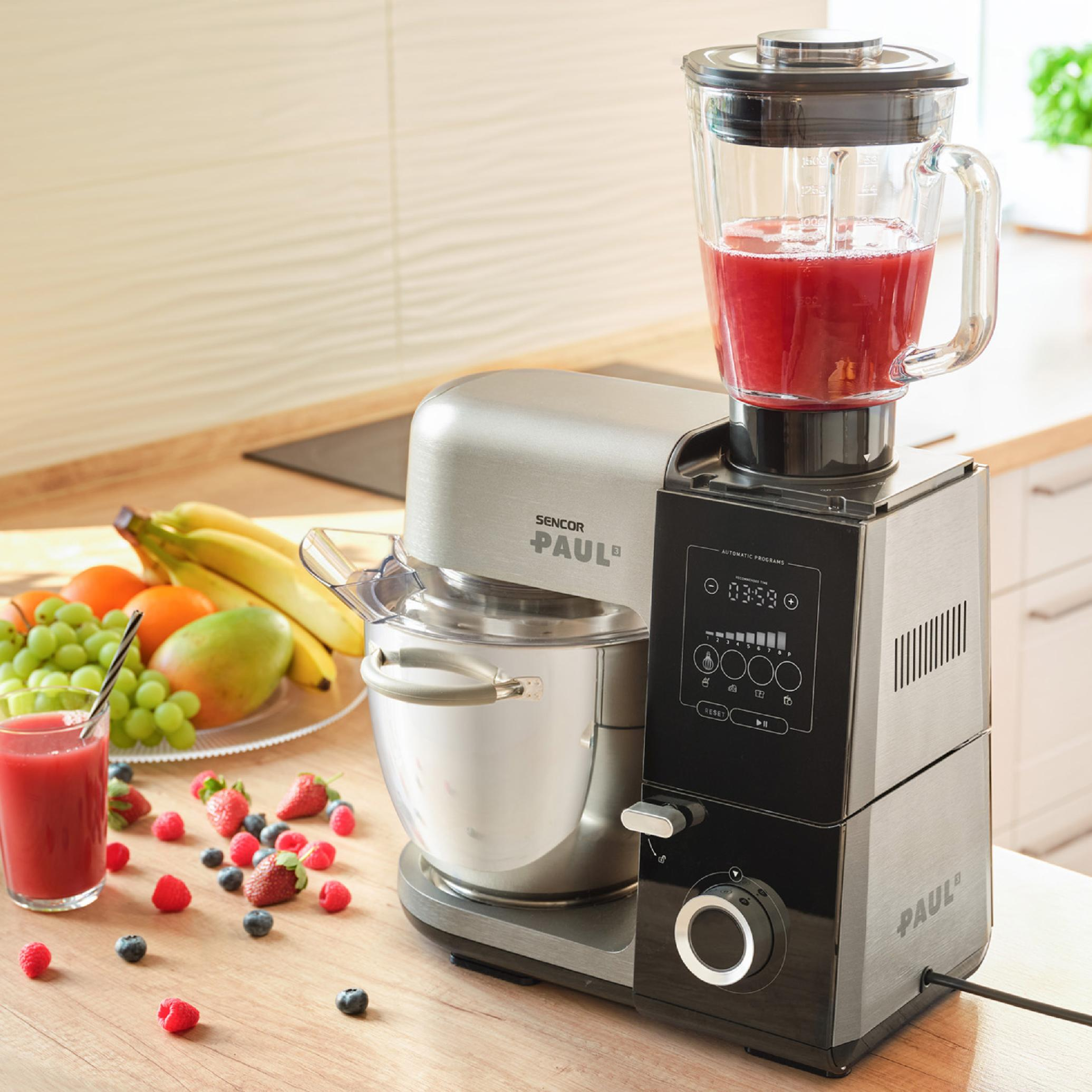 Robot kuchenny z czerwonym smoothie w blenderze i świeżymi owocami na drewnianym blacie.