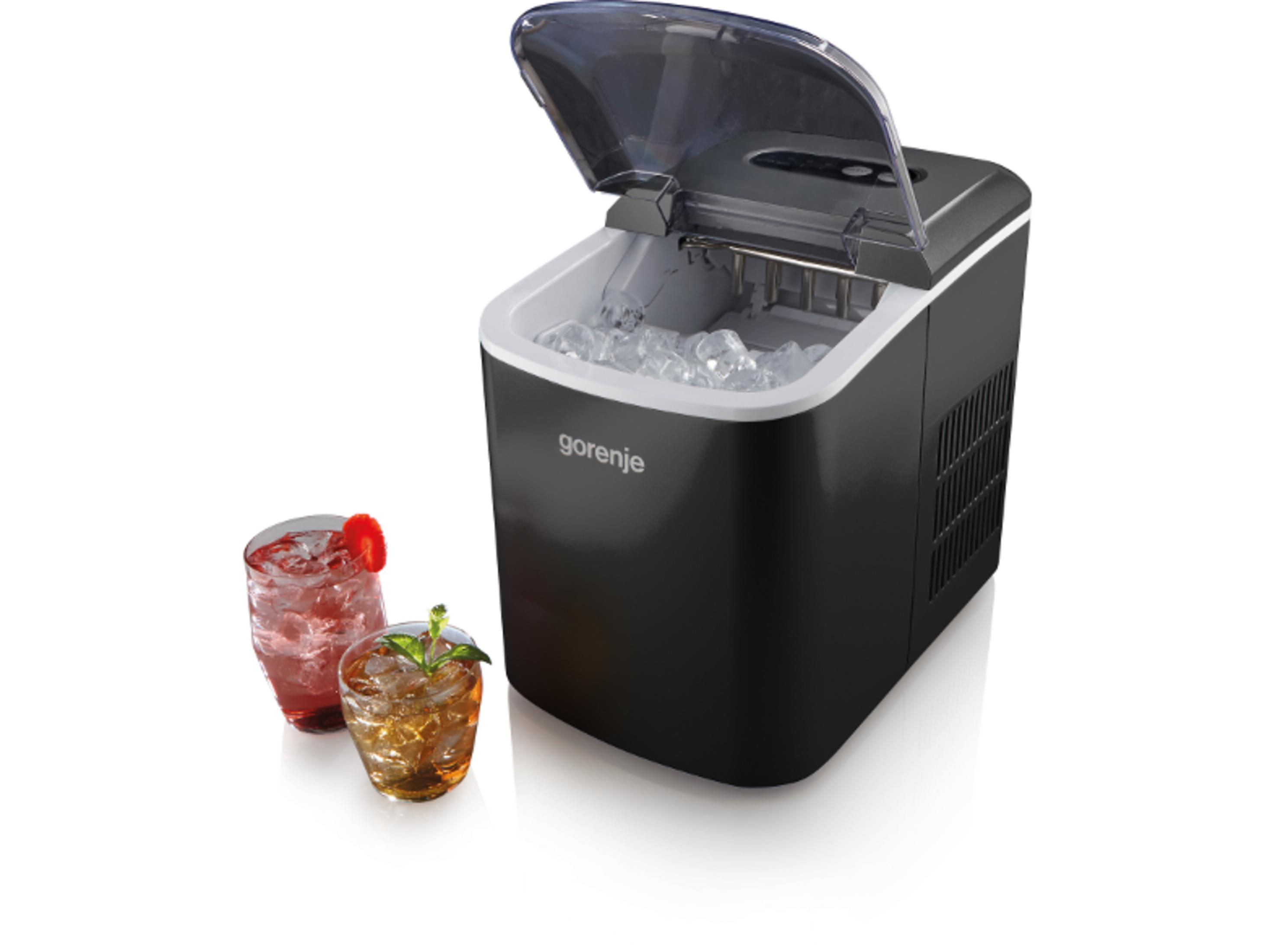 Fabricador de hielo negro Gorenje con tapa abierta y cubitos, junto a dos vasos de bebidas frías.