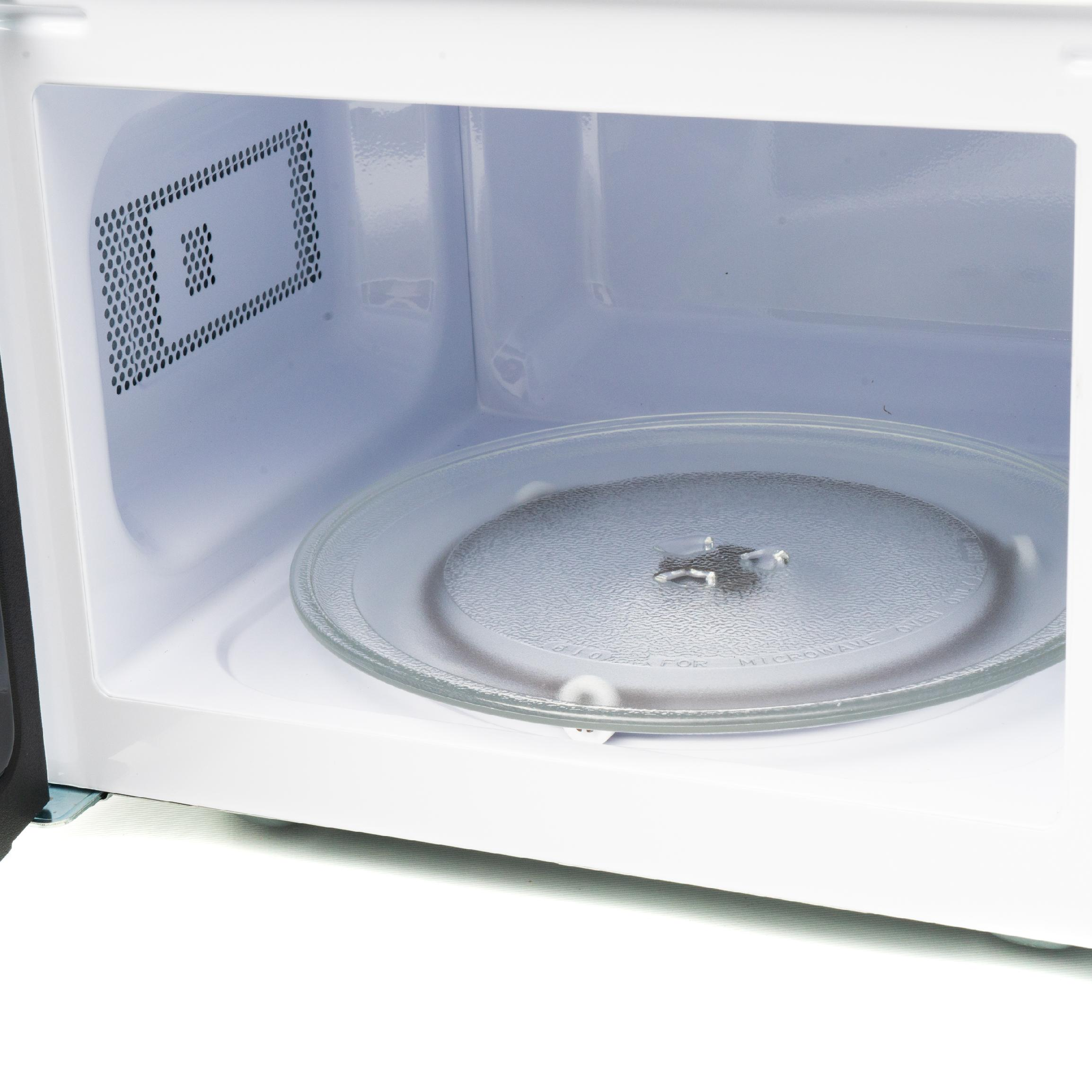El interior de un horno microondas blanco y limpio con un plato giratorio de vidrio.