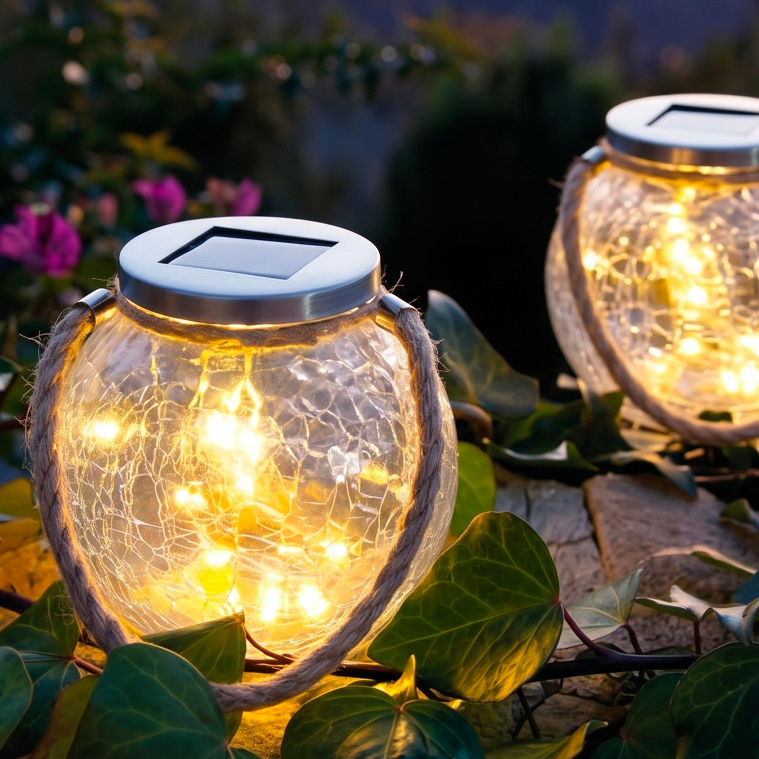 Due lanterne solari rotonde con luci calde e manici in corda in un giardino.