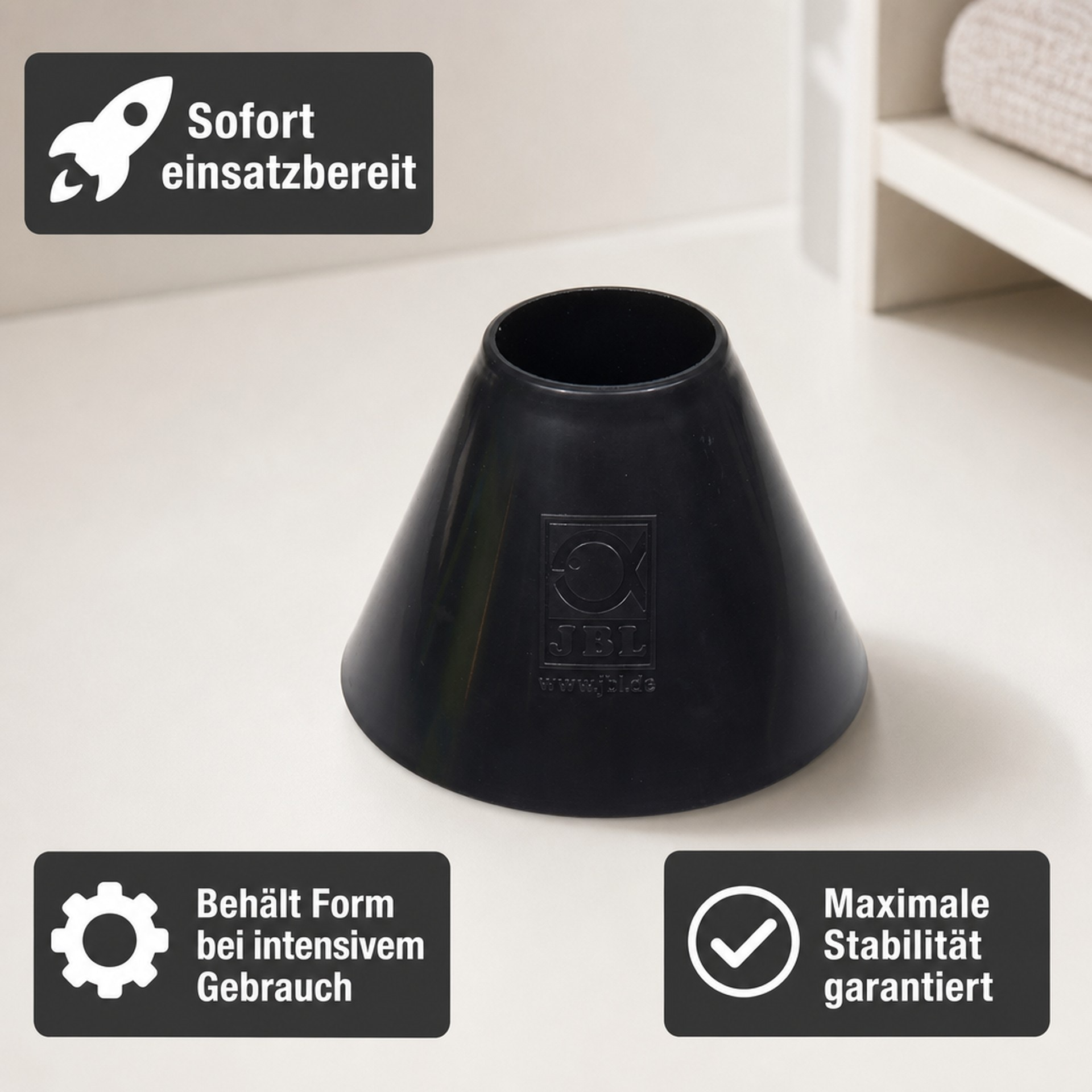 Un cono in gomma JBL nero su superficie chiara con tre box.