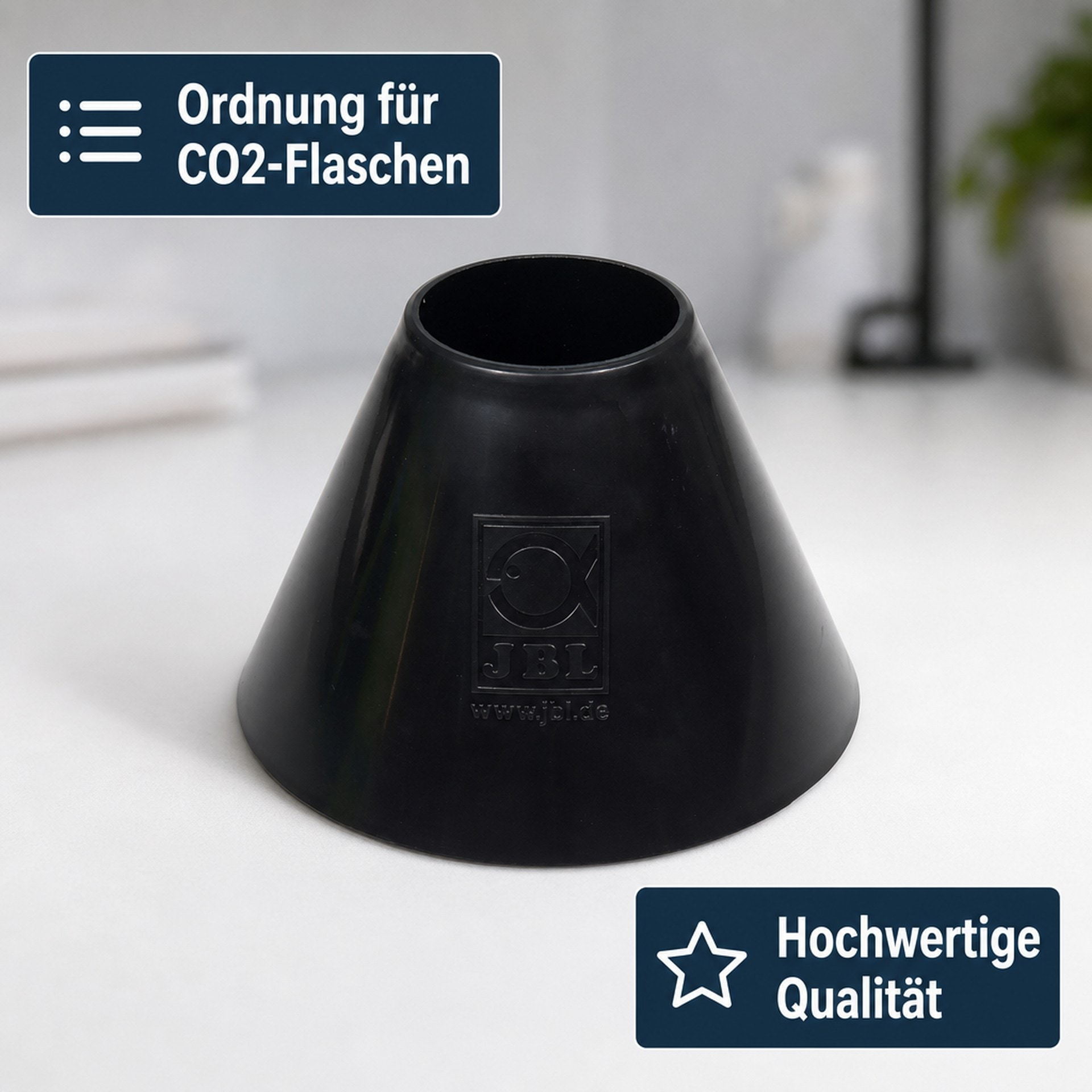 Un supporto JBL nero di forma conica per bombole di CO2 si trova su un tavolo bianco.