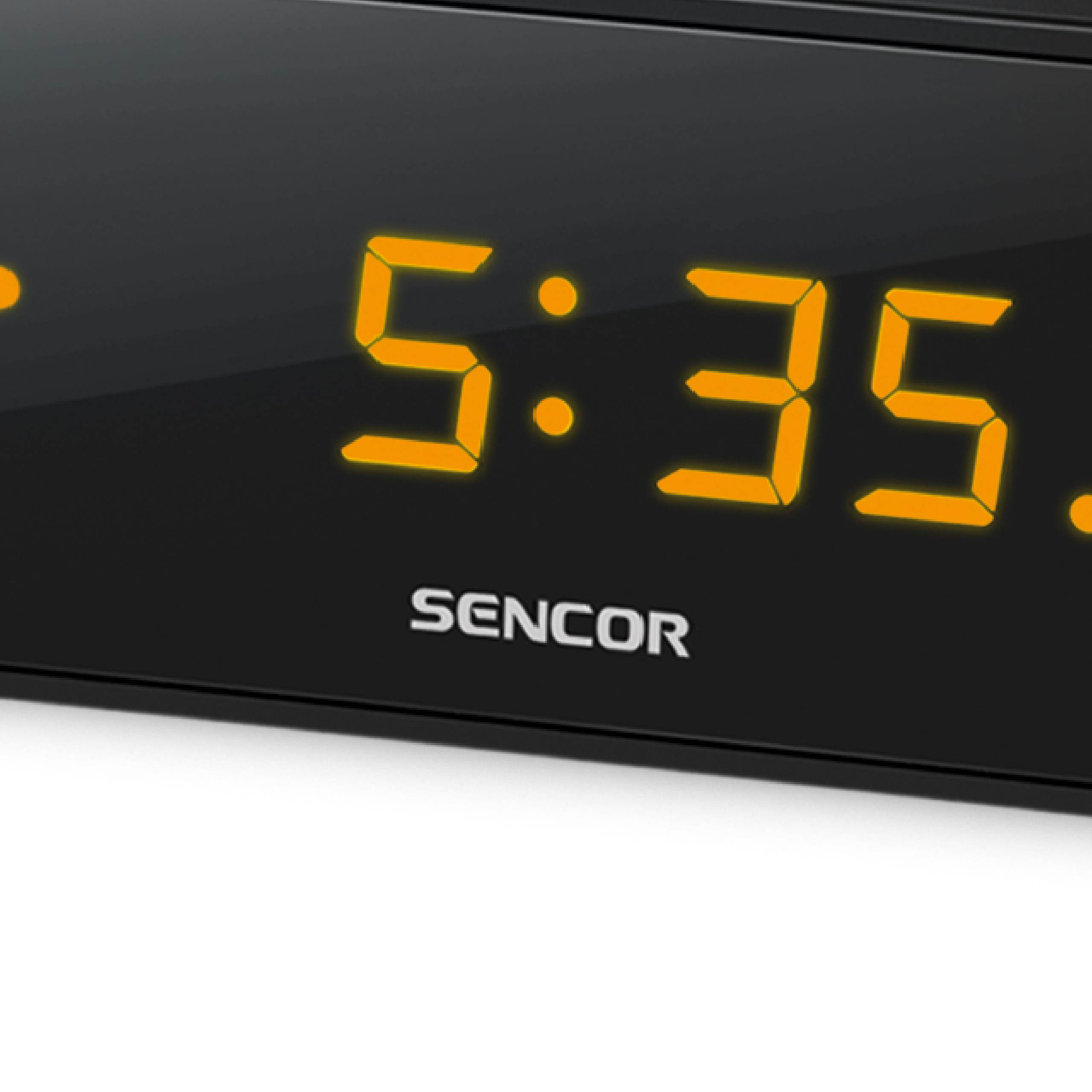 Un reloj digital Sencor negro muestra las 5:35 en dígitos amarillos brillantes.