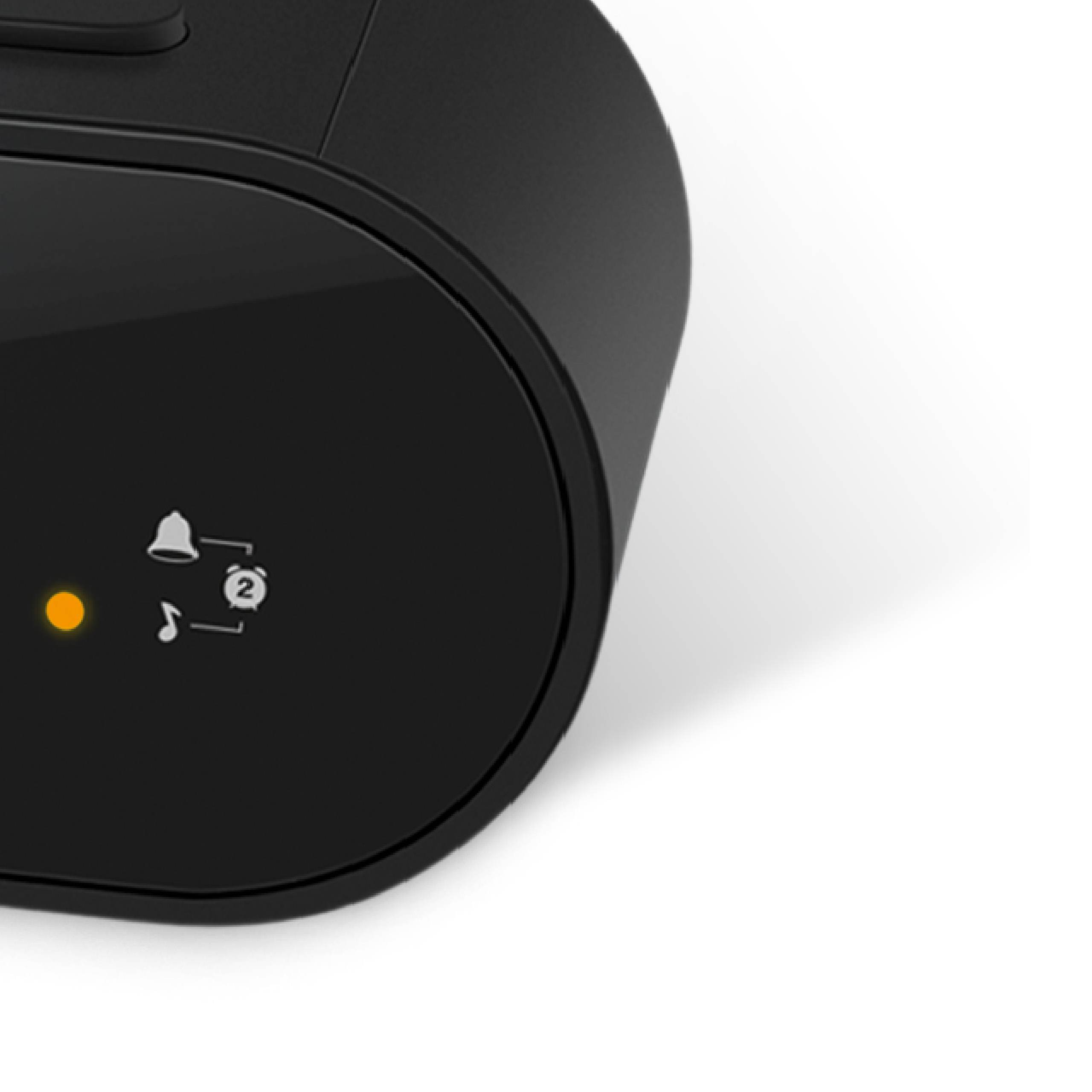 Primer plano de un reloj negro con iconos de alarma y música y un punto de luz naranja.