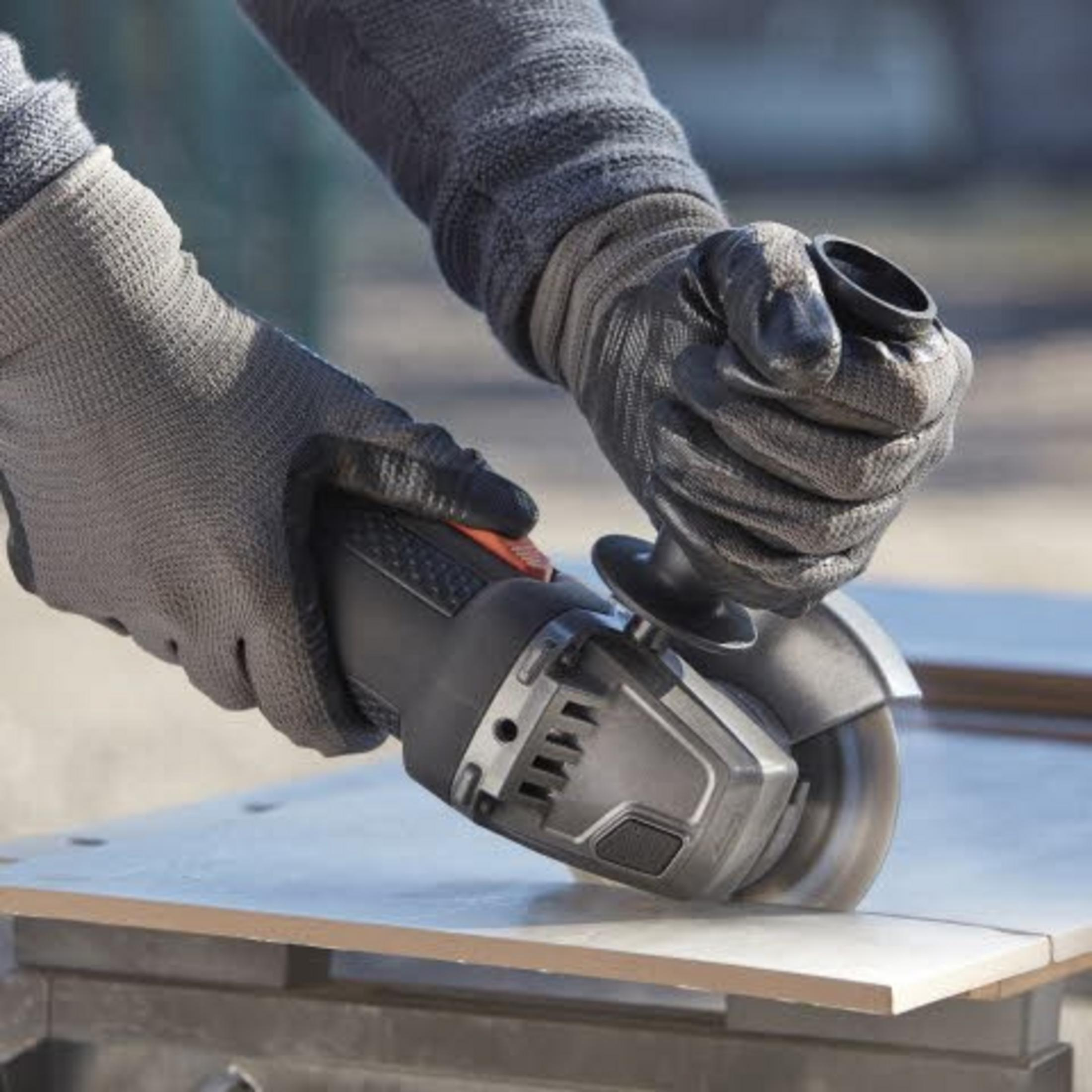 Manos con guantes cortan un azulejo usando una amoladora angular.