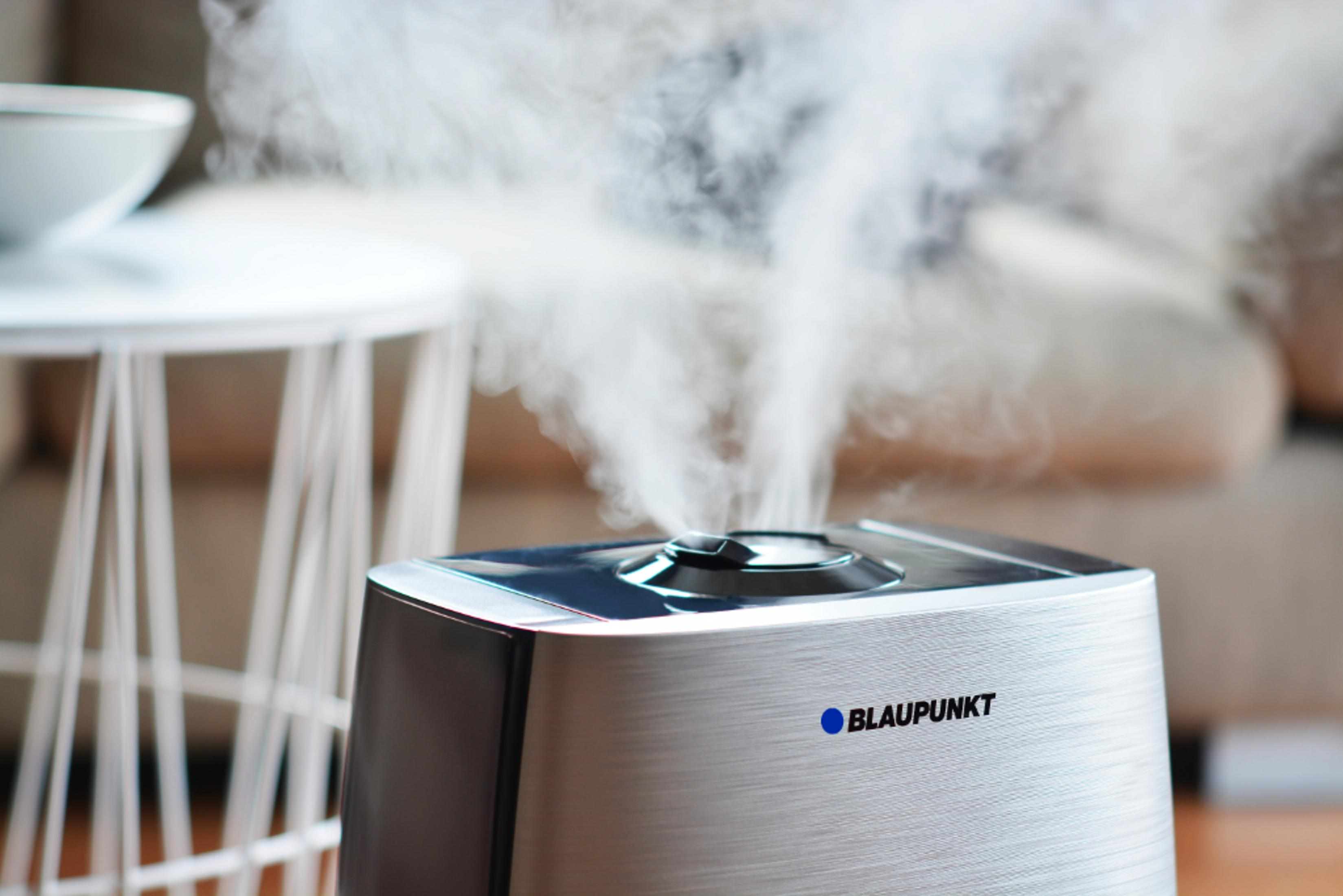 Un humidificador plateado Blaupunkt libera un flujo denso de vapor blanco en una habitación.