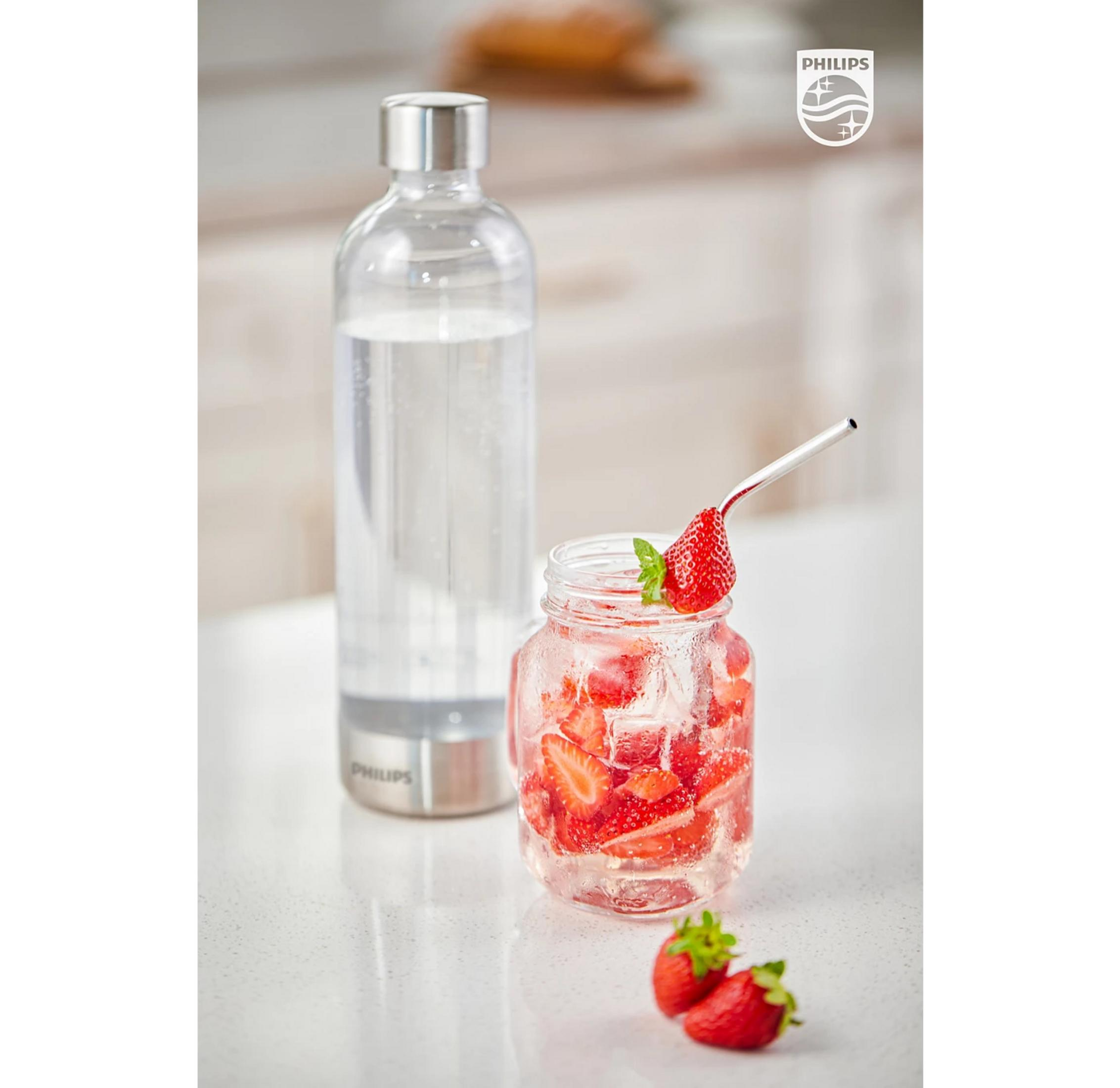 Bottiglia di vetro con acqua frizzante e barattolo di limonata alle fragole con cannuccia.