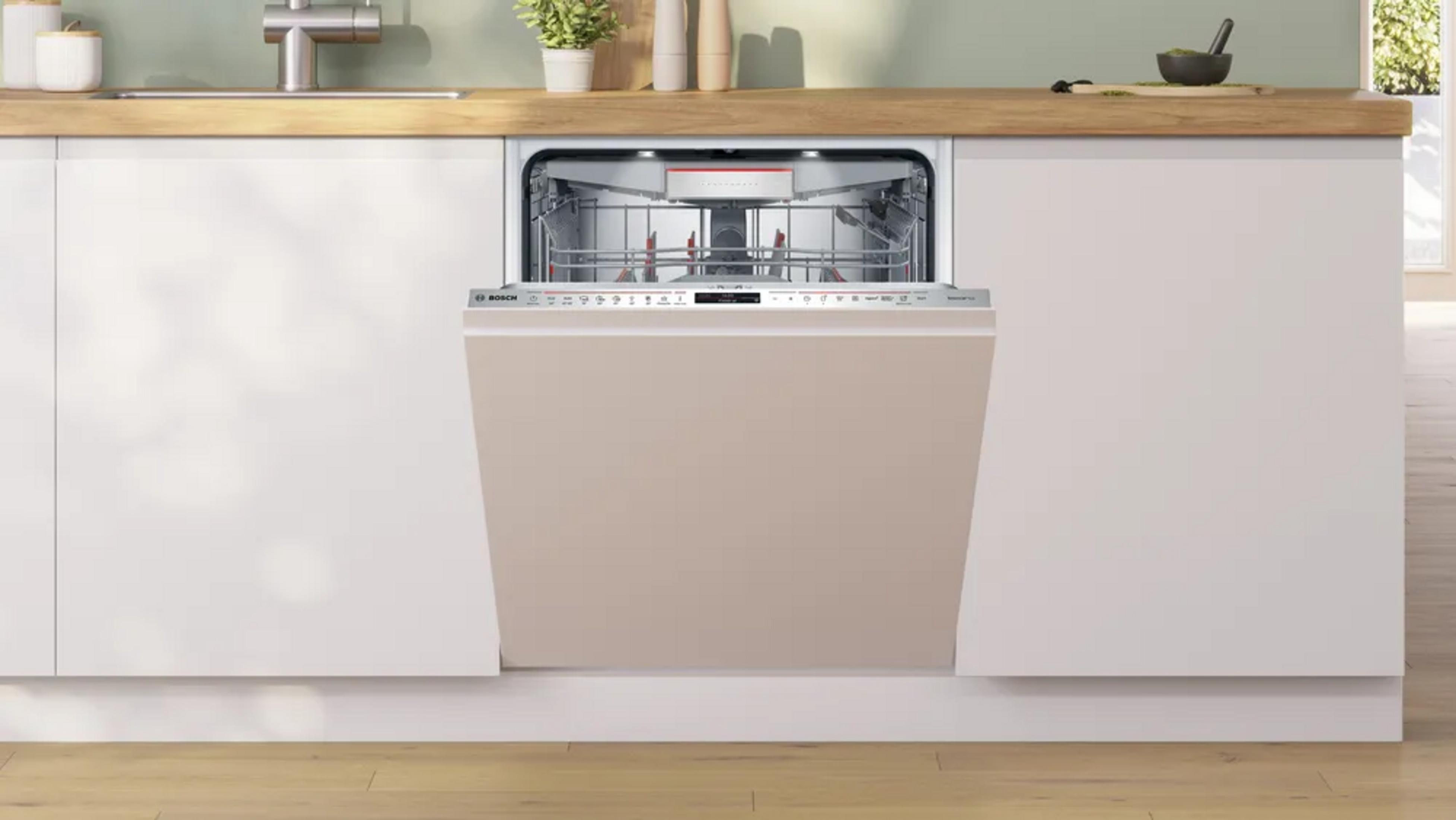 Una lavastoviglie Bosch beige aperta è integrata in un mobile da cucina bianco con piano di lavoro in legno.