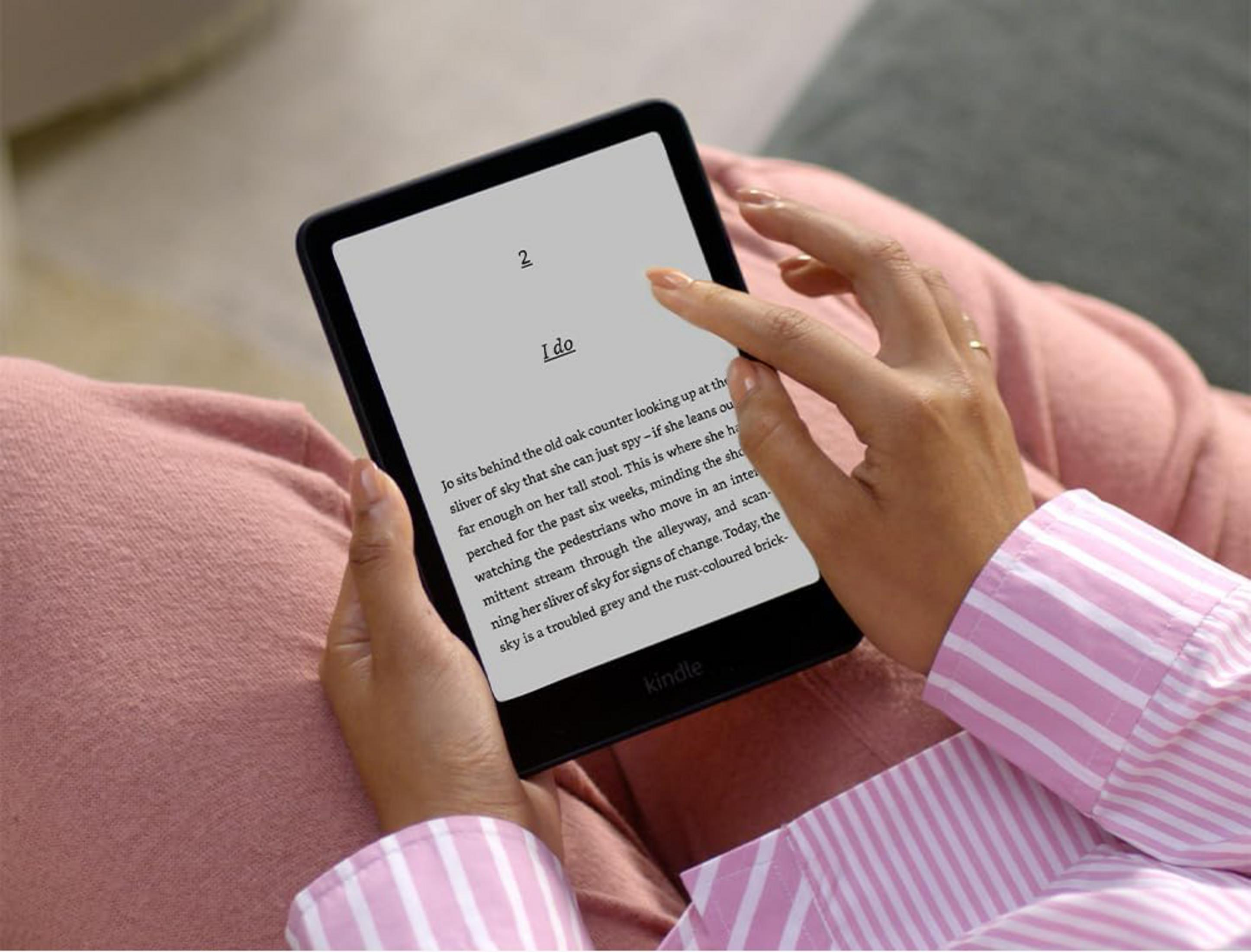 Una persona con una camicia rosa tiene un e-reader e legge.