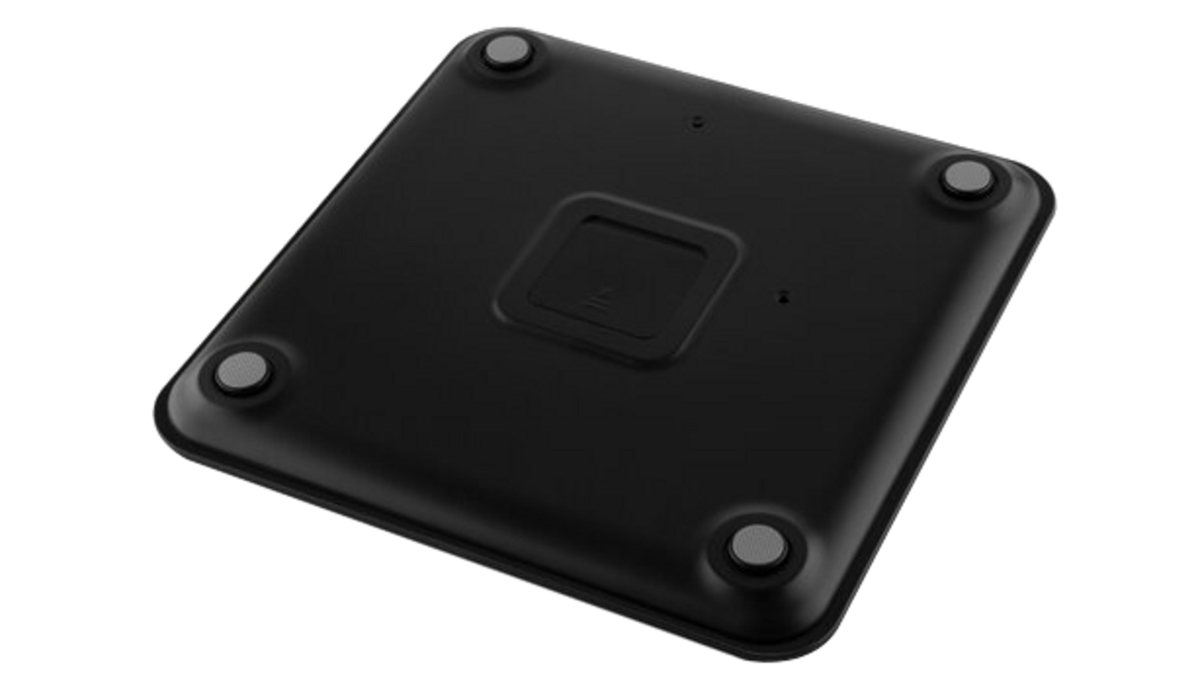 Il fondo di una bilancia pesapersone nera con quattro piedini grigi rotondi e vano batterie centrale.