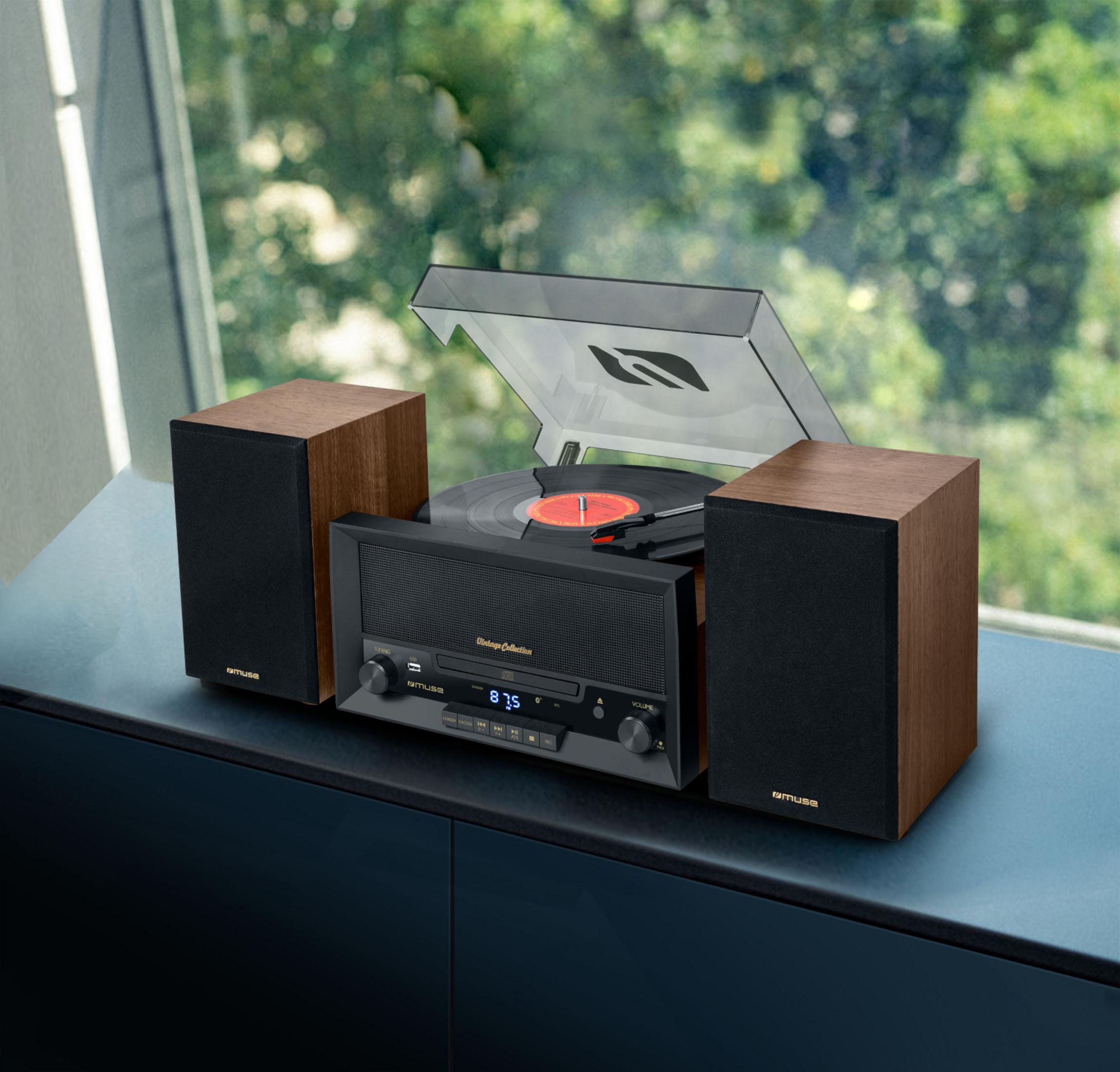 Un tocadiscos vintage con dos altavoces de madera en una mesa ante una ventana.