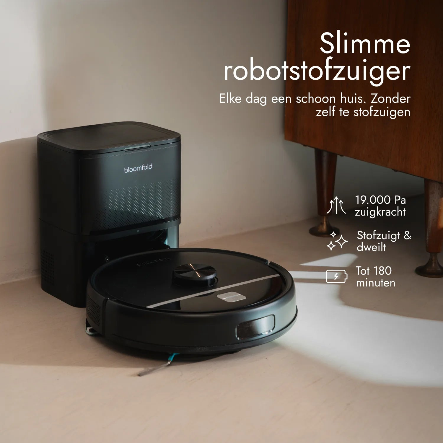 Ein schwarzer Bloomfold Saugroboter mit Ladestation auf hellem Boden neben einem Holzschrank.