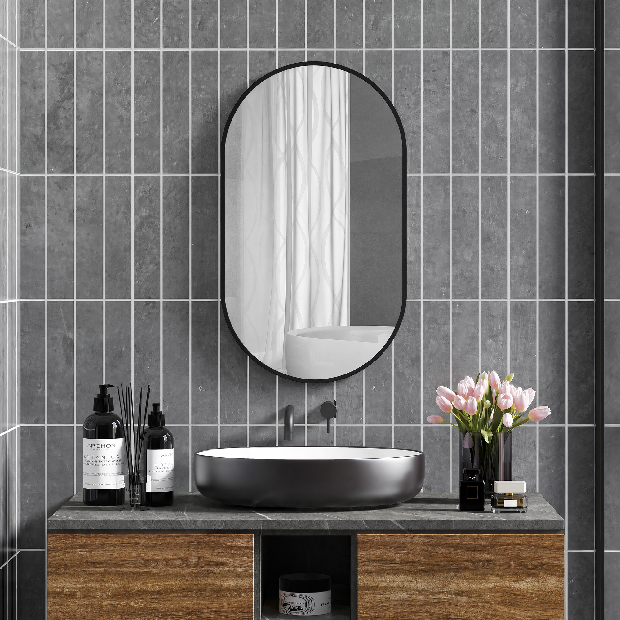 Un baño moderno con lavabo oscuro, espejo ovalado en azulejos grises y tulipanes rosas.