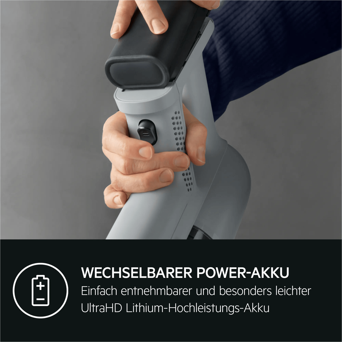 Eine Hand setzt einen Akku in einen grauen Staubsauger ein. Unten steht 'Wechselbarer Power-Akku'.