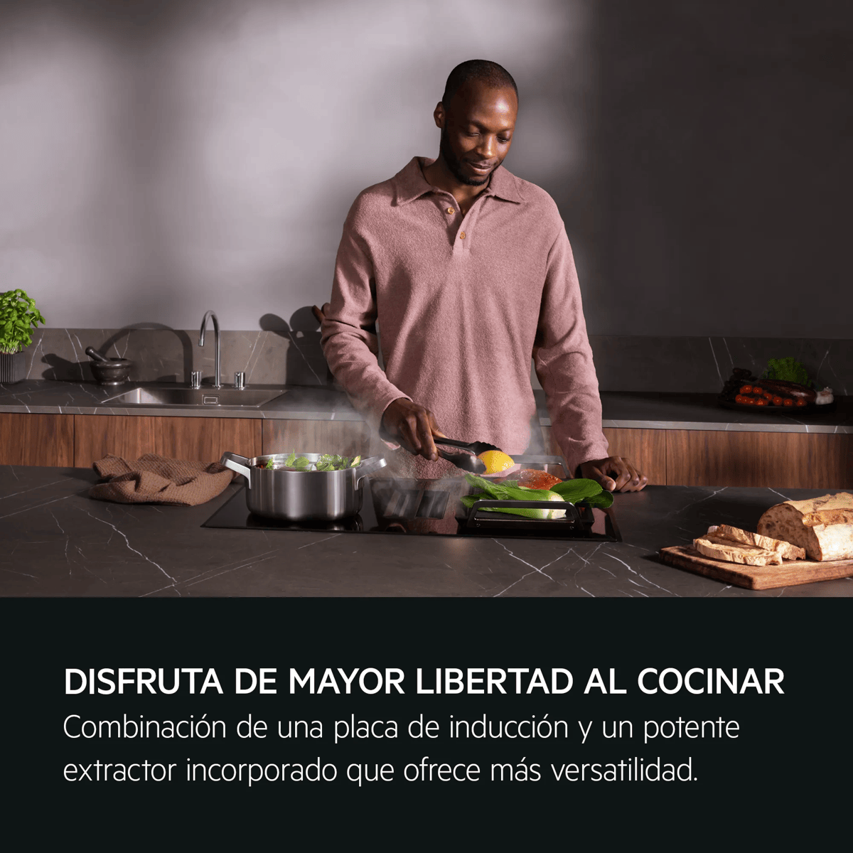 Un hombre cocina en una moderna placa de inducción con extractor integrado en una cocina elegante.
