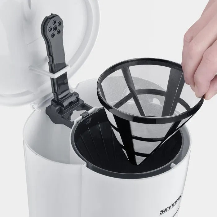Una mano coloca un filtro de café en una cafetera blanca.