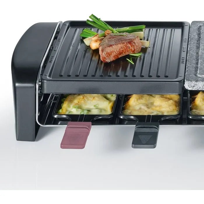 Ein Raclette-Grill mit Steak und Gemüse oben sowie geschmolzenem Käse in den Pfännchen unten.