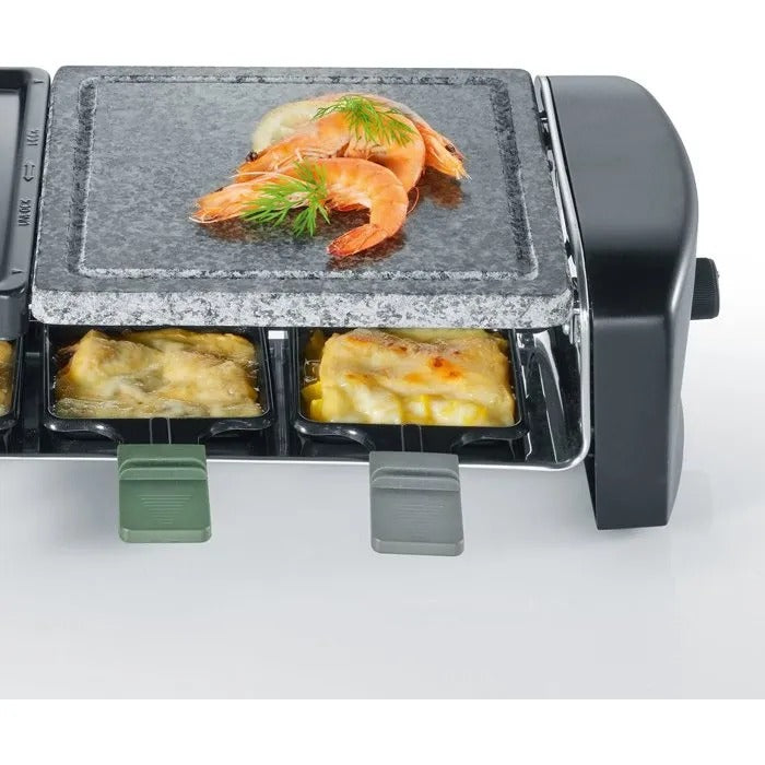 Ein Raclette-Grill mit einer Steinplatte oben und garnierten Shrimps, unten schmelzender Käse in kleinen Pfännchen.