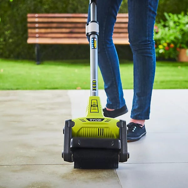Una persona usa un limpiador de patios Ryobi verde lima en una superficie.