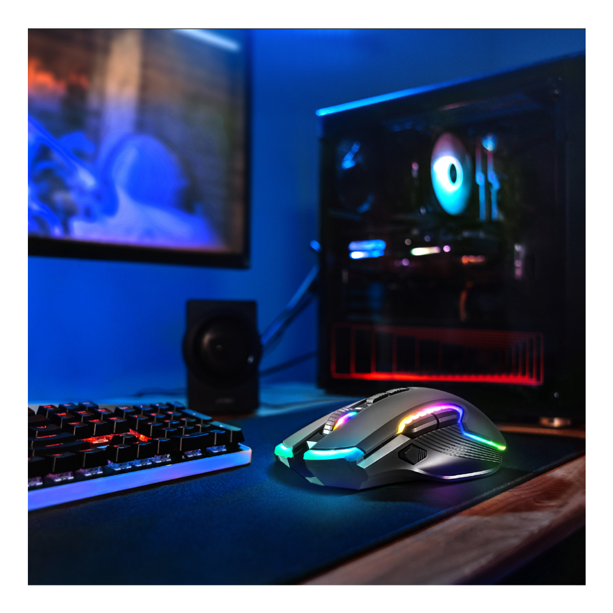 Eine leuchtende RGB-Gaming-Maus auf dem Schreibtisch mit Tastatur, Lautsprecher, PC-Tower und Monitor in einem blau beleuchteten Zimmer.