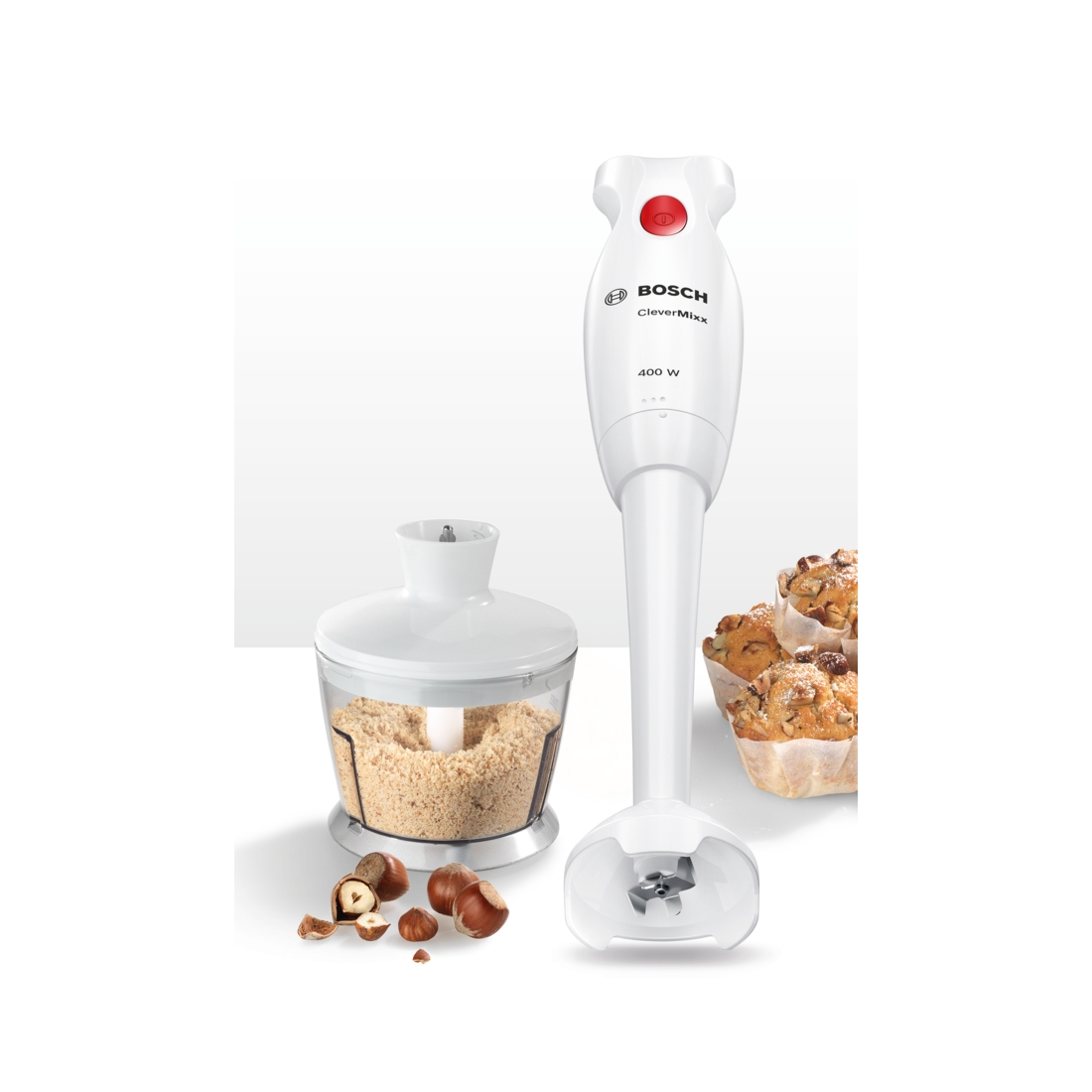 Biały blender ręczny Bosch z rozdrabniaczem, orzechami i muffinkami na stole.