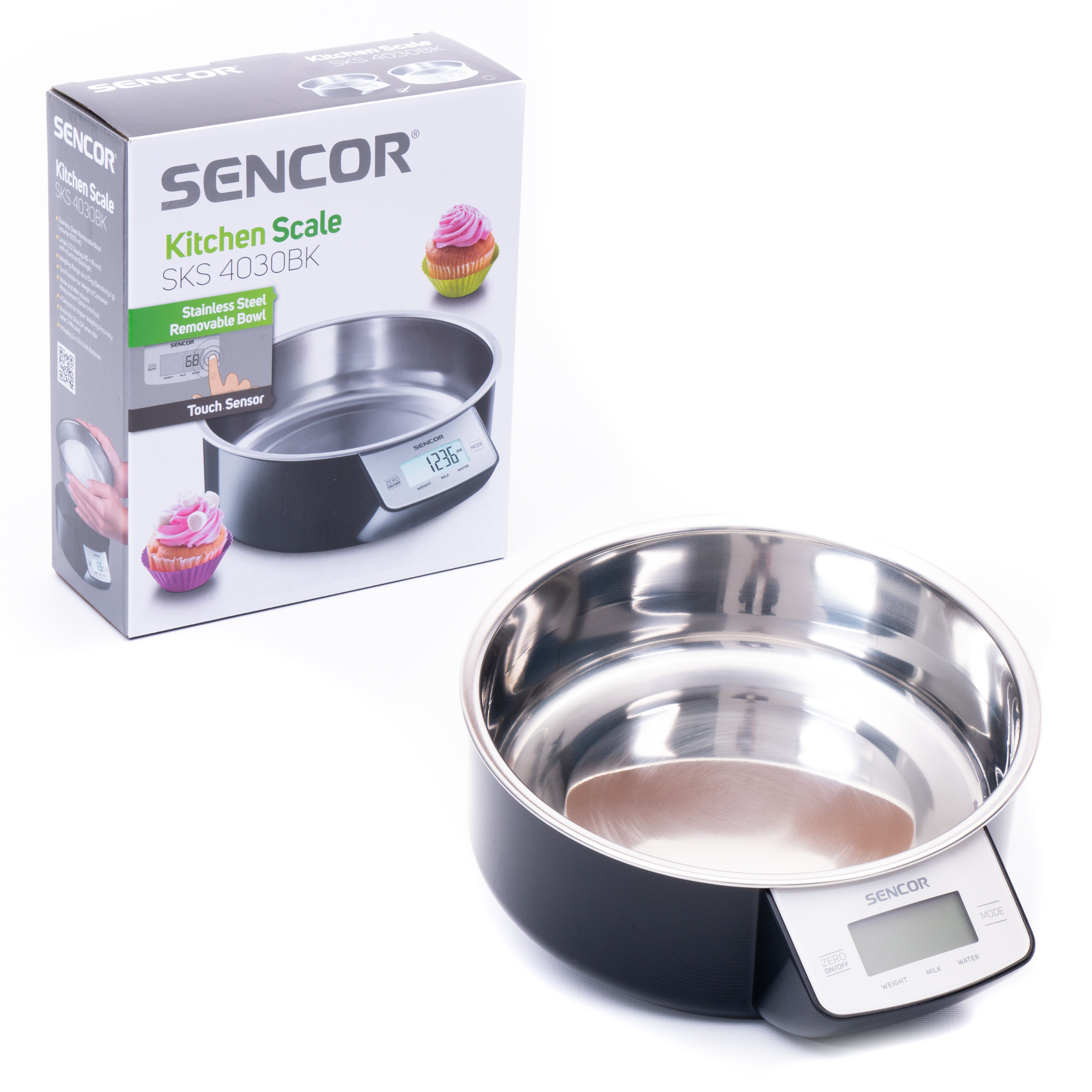 Una balanza de cocina Sencor negra con bol de acero inoxidable junto a su caja.