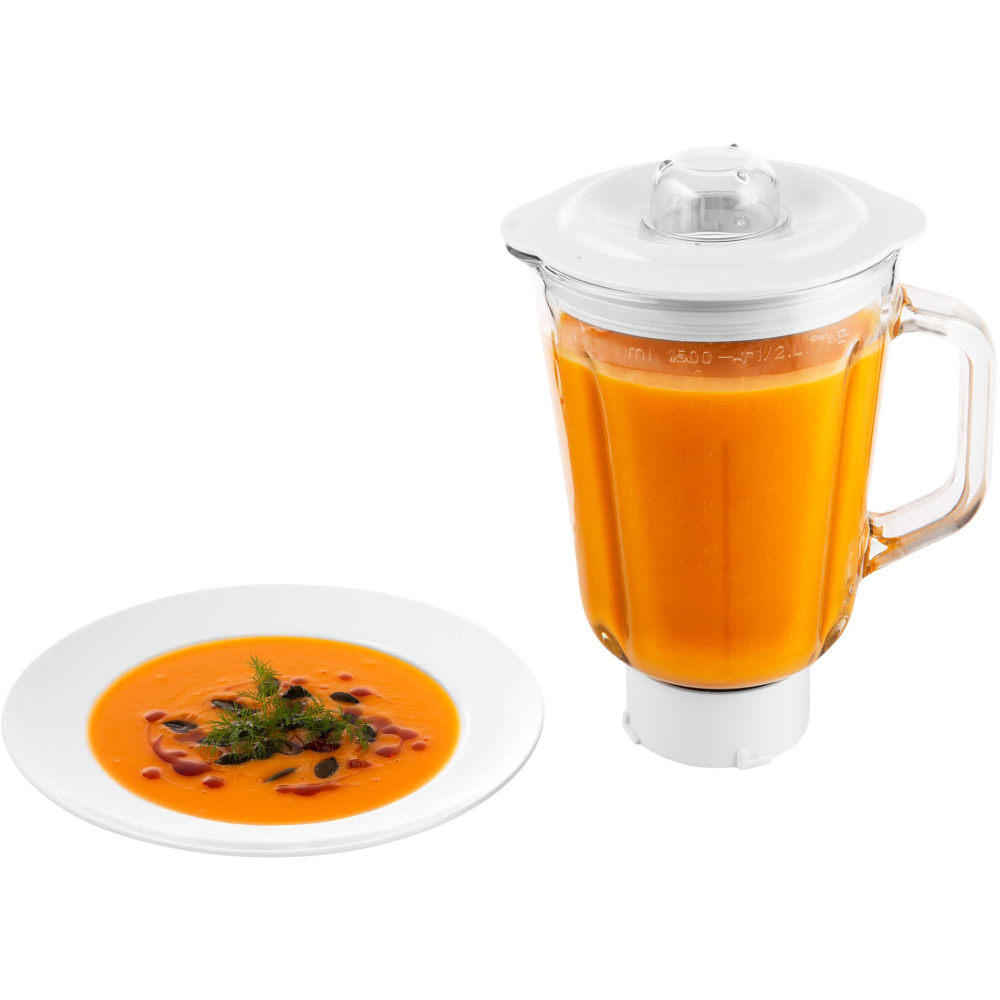 Blender wypełniony pomarańczową zupą obok białego talerza z tą samą zupą posypaną ziołami.