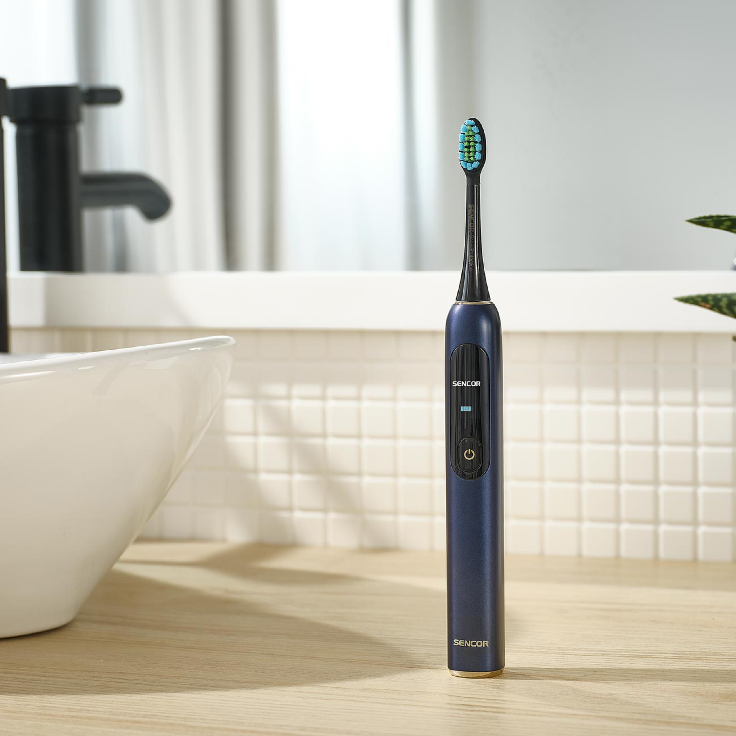 Un cepillo de dientes eléctrico azul oscuro sobre una encimera de madera en un baño luminoso.