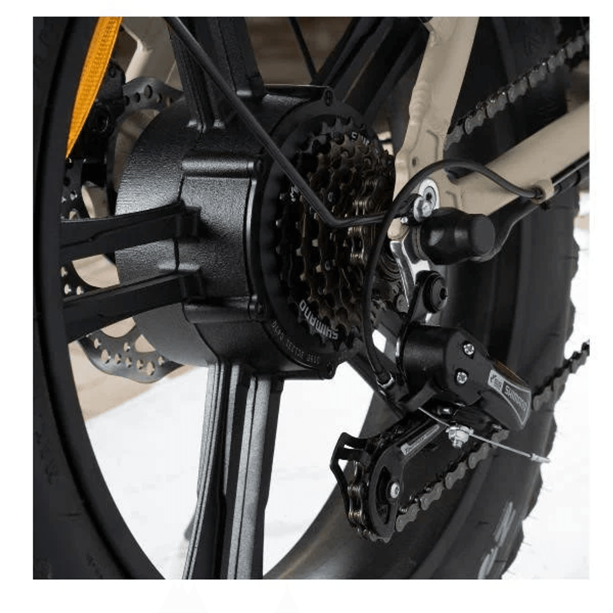 Primer plano de la rueda trasera de una bicicleta con motor negro, marchas, cadena y freno de disco.