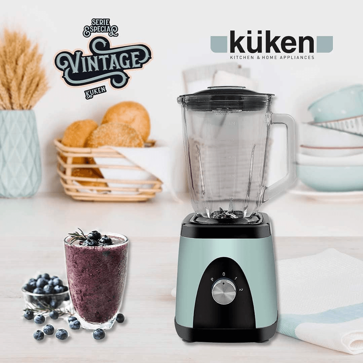 Ein mintgrüner Küken Vintage-Standmixer steht auf einem Tisch neben einem Glas Smoothie und frischen Blaubeeren.