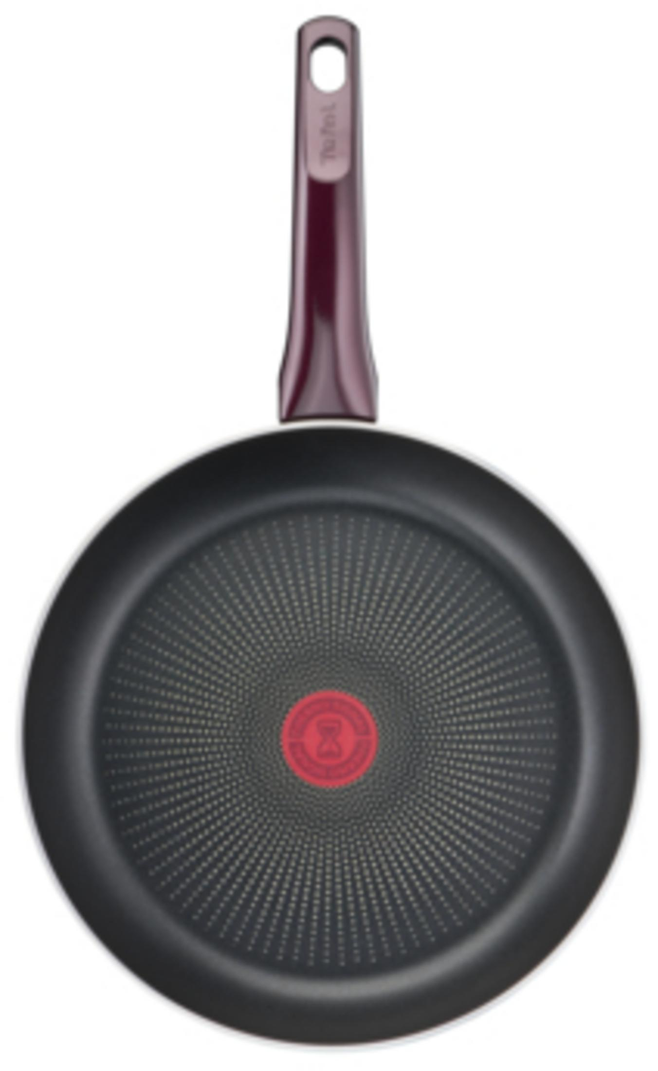 Eine schwarze Bratpfanne mit rotem Hitzesensor in der Mitte und violettem Griff vor weißem Hintergrund.