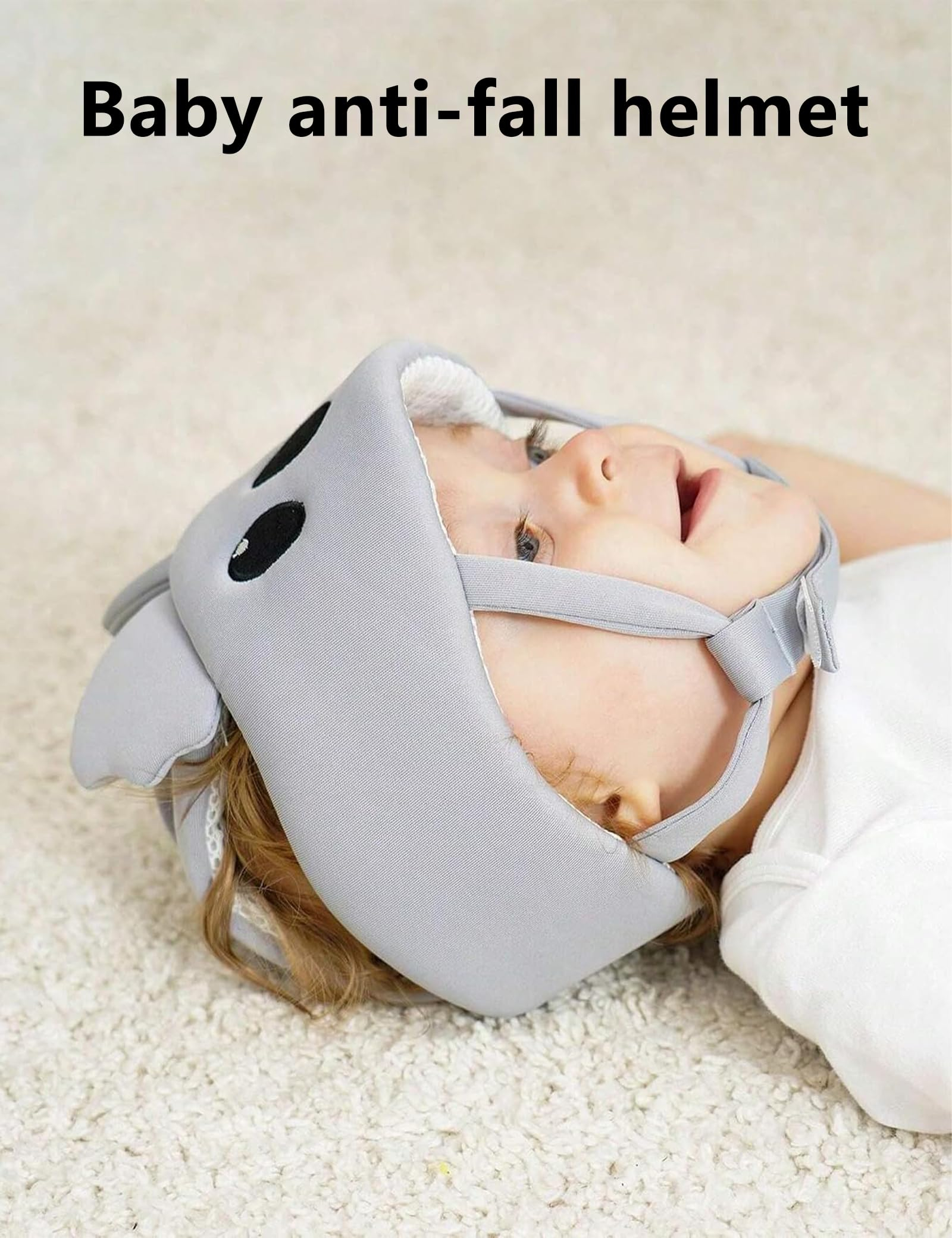 Ein Baby liegt auf einem weißen Teppich und trägt einen grauen Schutzhelm mit kleinen Ohren.