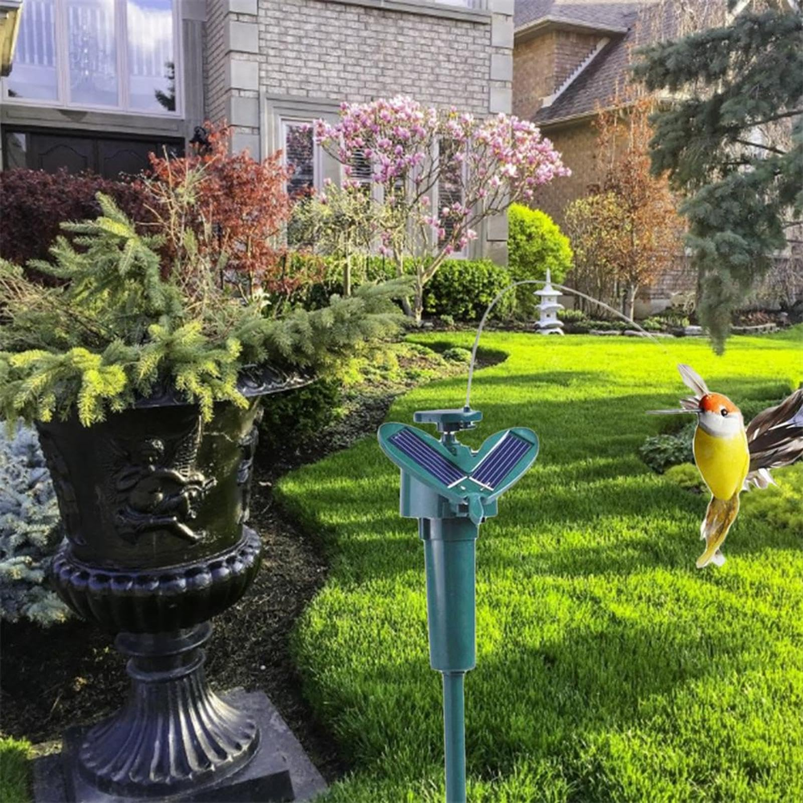 Solarbetriebener Springbrunnen auf dem Rasen neben einer schwarzen Urne und Haus.