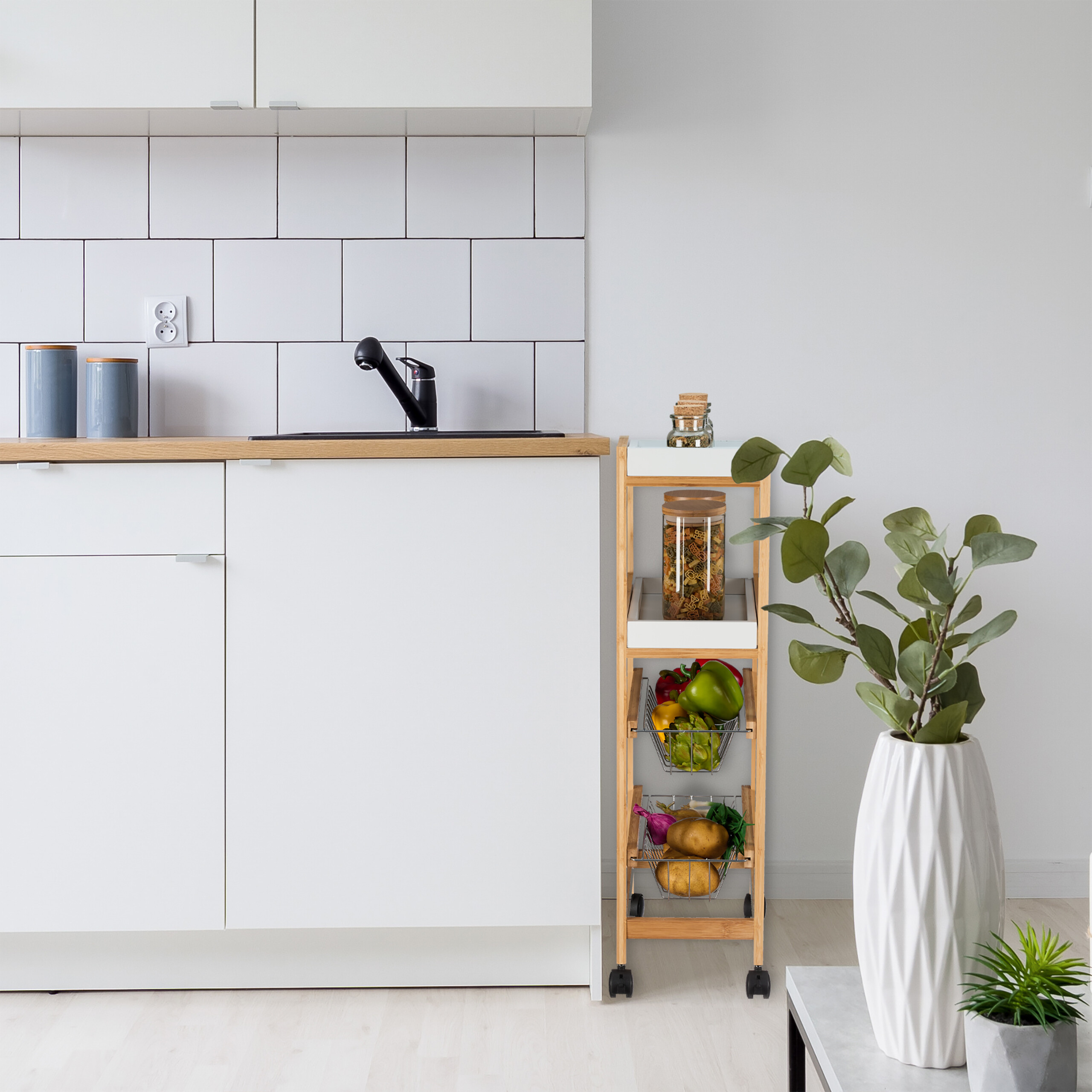 Moderne Küche mit weißen Möbeln, Holztresor, Rollwagen mit Gemüse und großer Vase mit grünen Blättern.