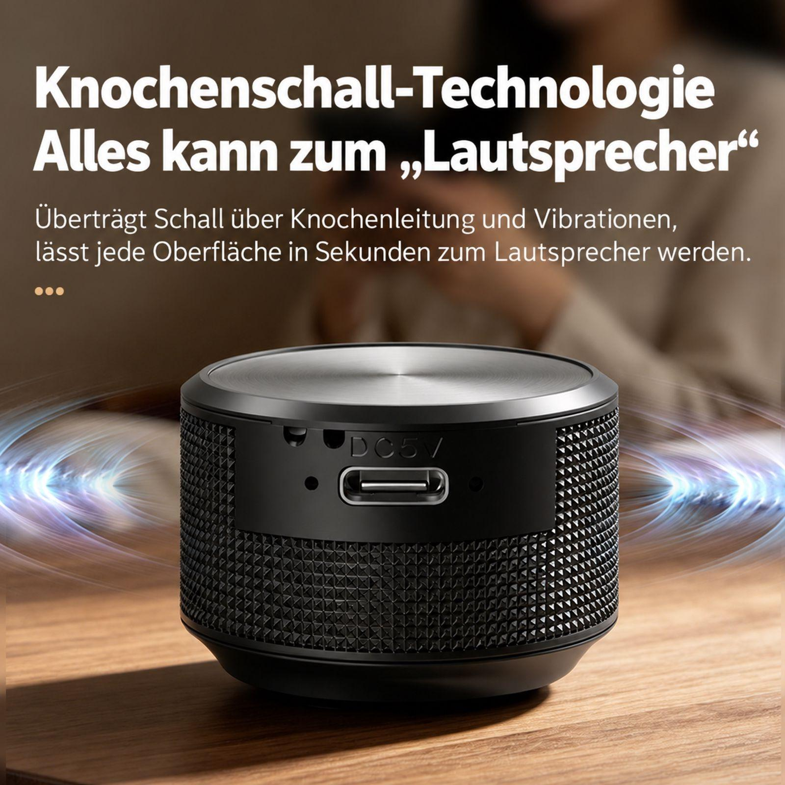 Ein kleiner schwarzer Knochenschall-Lautsprecher steht auf einem Holztisch mit deutscher Textüberlagerung.