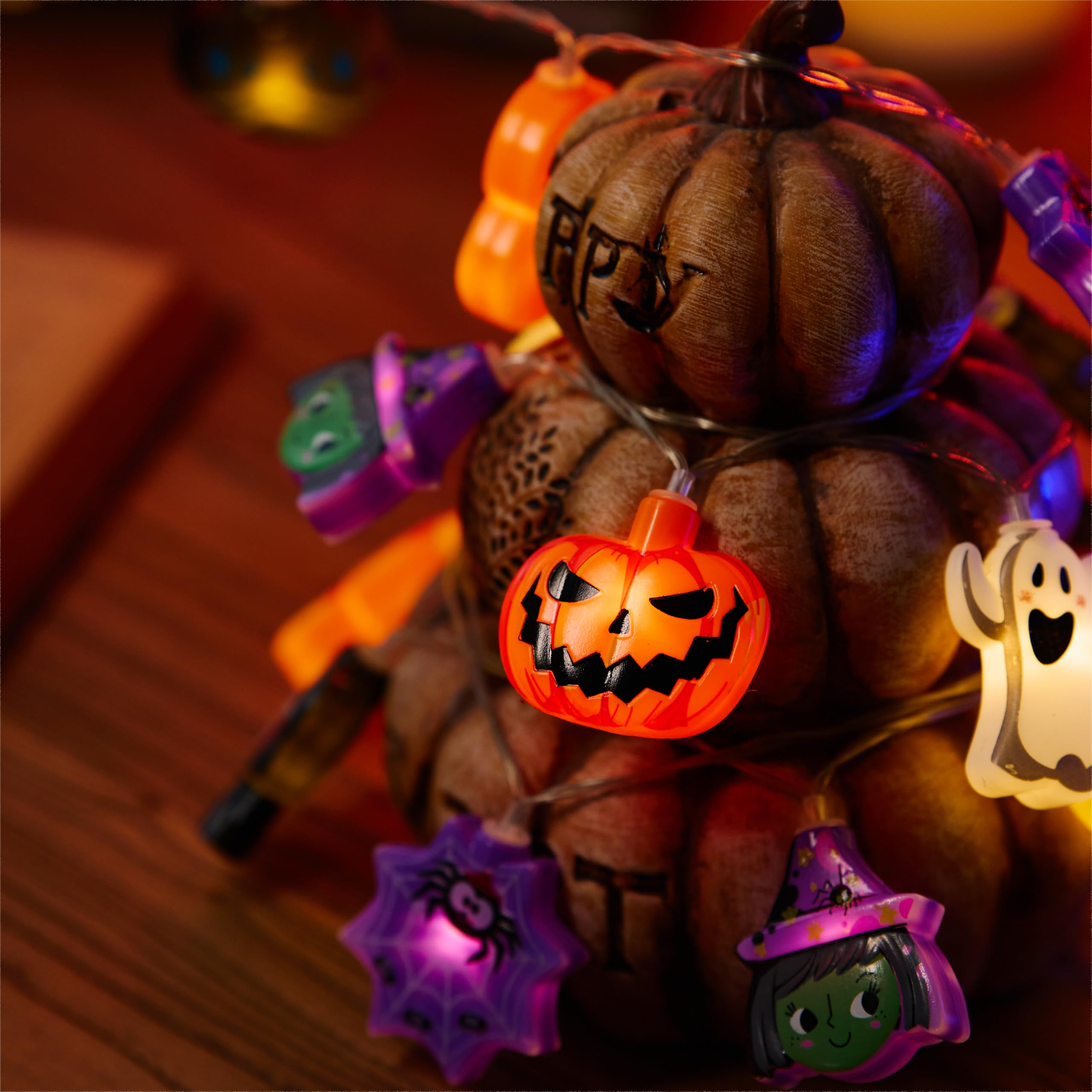 Stapel aus dekorierten Kürbissen mit bunten Halloween-Lichterketten.