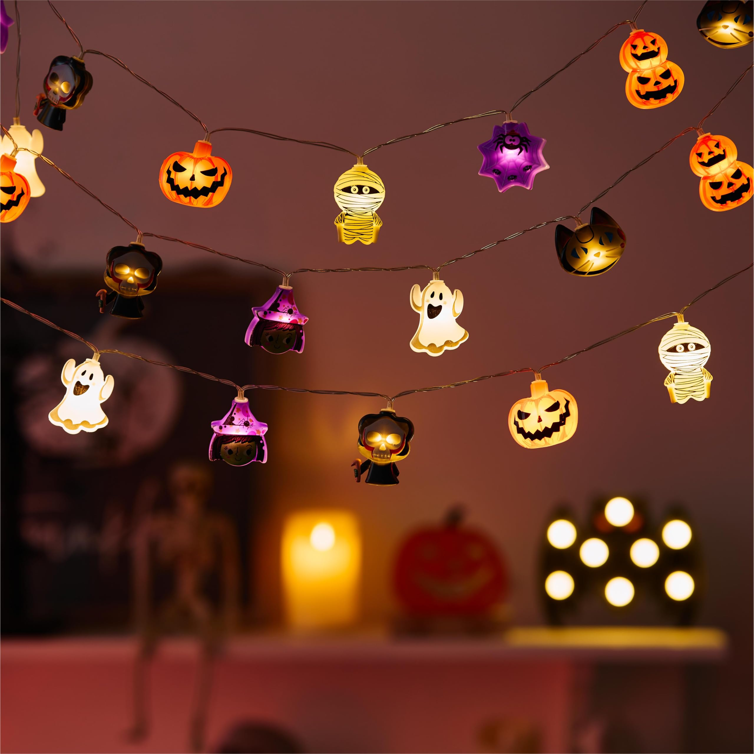 Leuchtende Halloween-Lichterketten in Form von Kürbissen, Geistern und Mumien hängen in einem Raum.