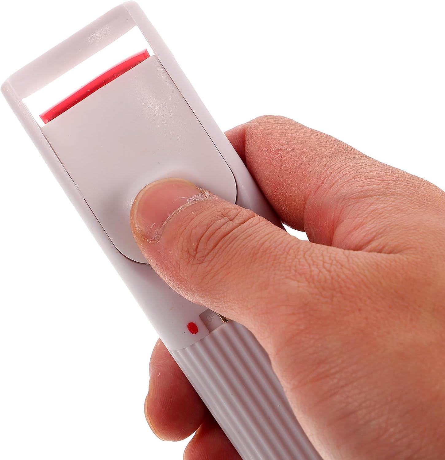Eine Hand hält eine weiße beheizbare Wimpernzange, der Daumen drückt den Ein- Ausschalter auf weißem Hintergrund.