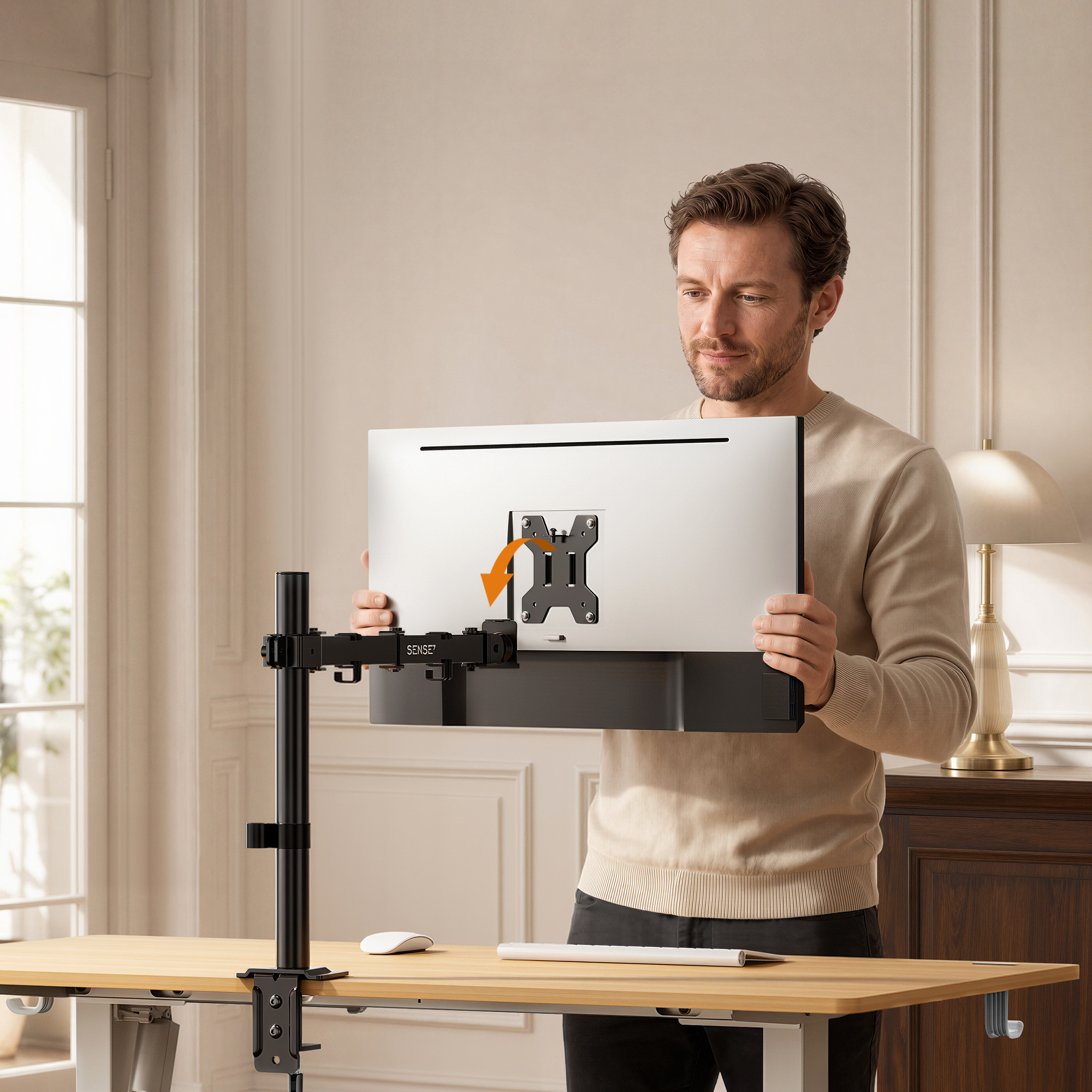 Ein Mann hält einen Monitor vor einen Schreibtisch mit einem schwarzen Monitorarm in einem hellen Raum.