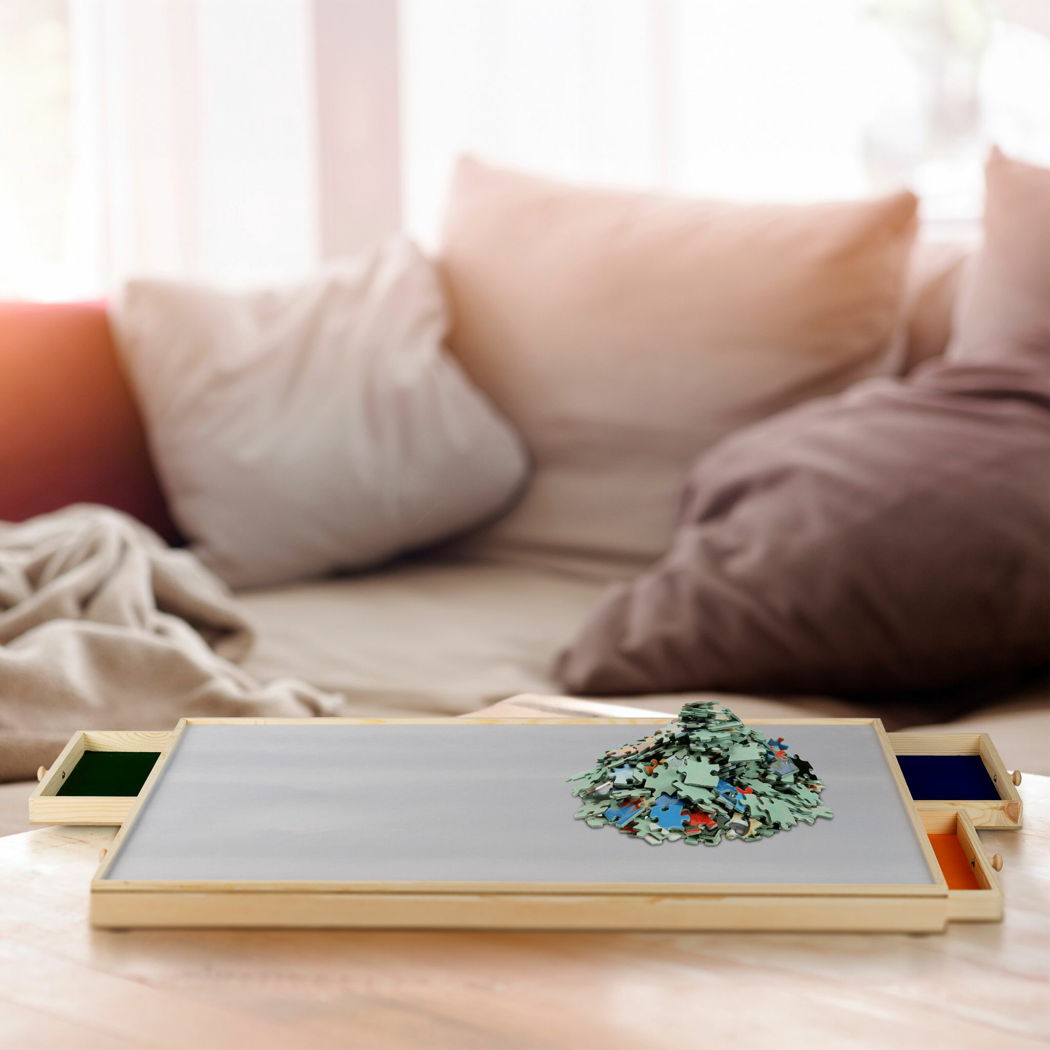 Ein hölzernes Puzzleschloss mit einem großen Haufen Puzzleteile in der Mitte, vor einem gemütlichen Sofa.