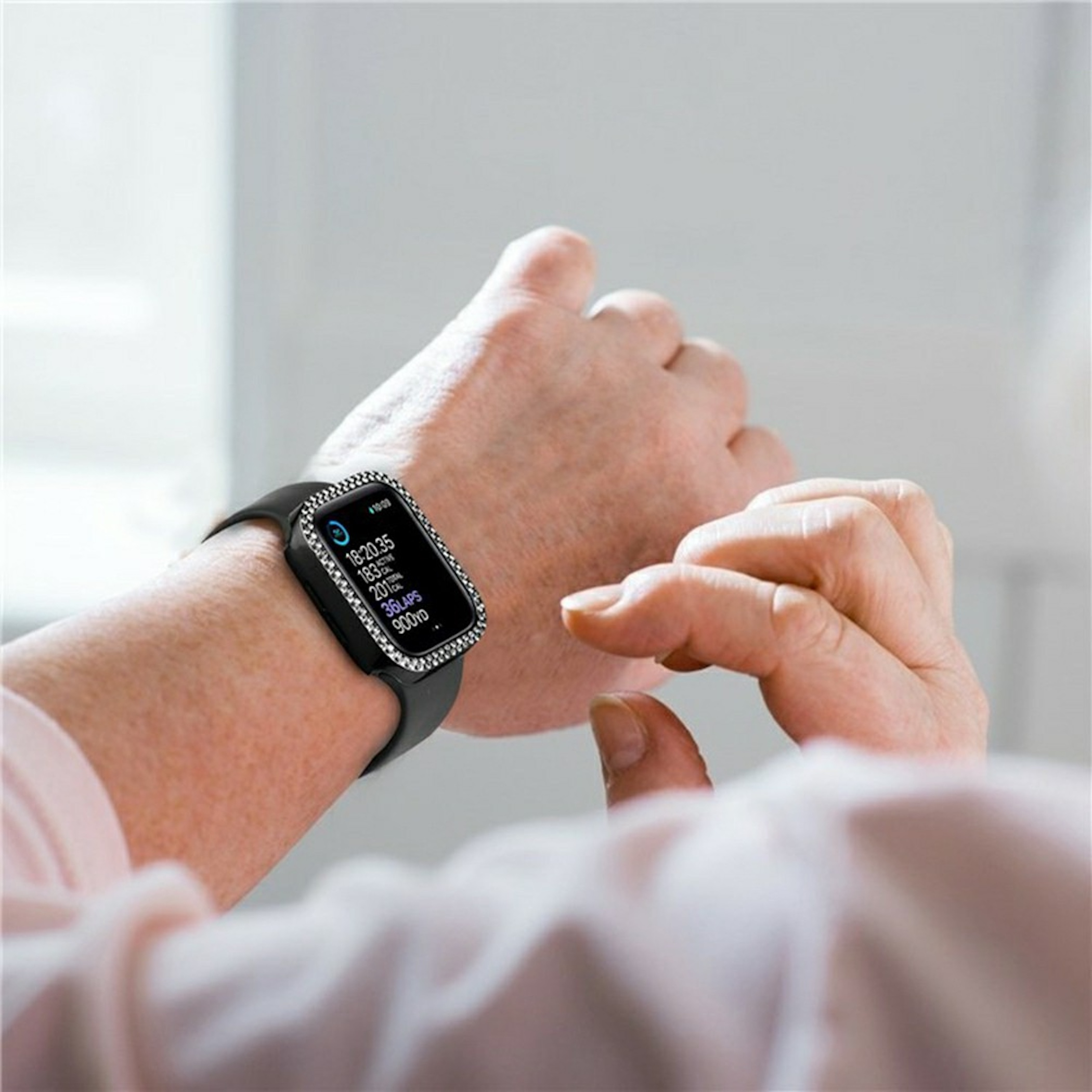 Eine Person trägt eine schwarze Smartwatch mit einem glitzernden Rahmen am Handgelenk.