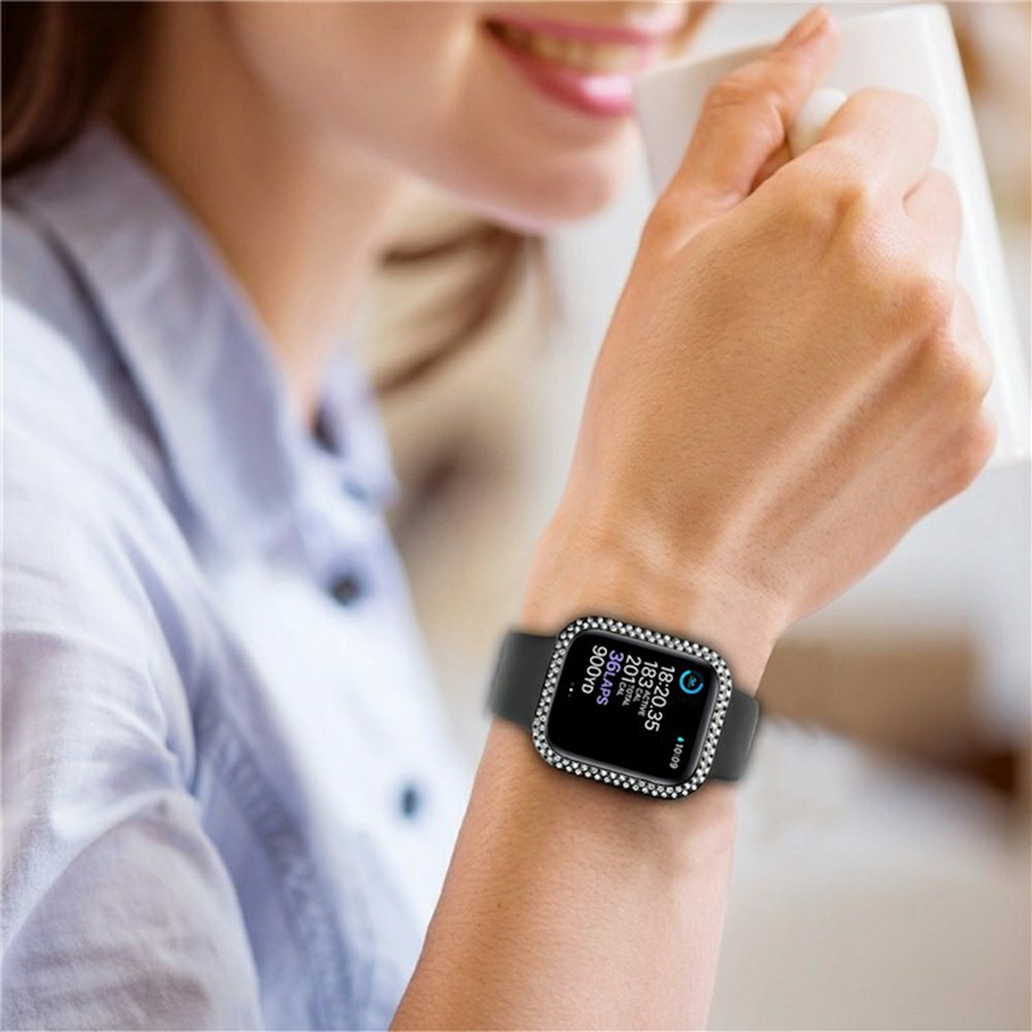 Eine Frau hält einen weißen Becher und trägt eine Smartwatch mit funkelnder Strass-Lünette.