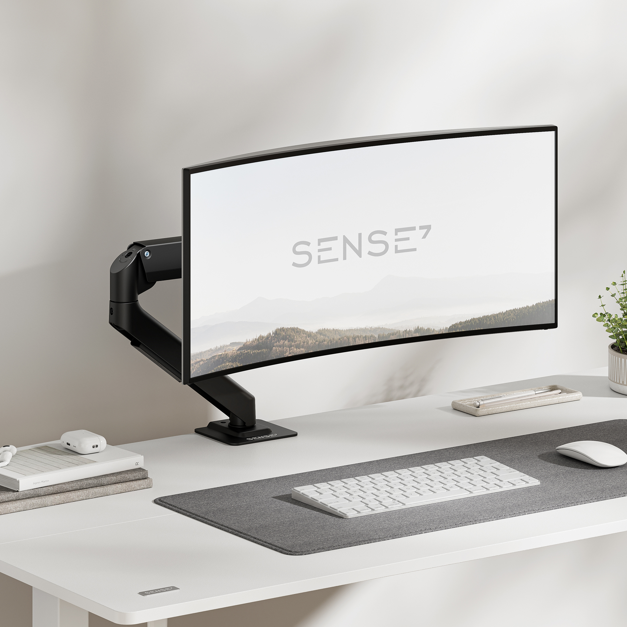 Ein gebogener Monitor an einem schwarzen Arm auf einem Schreibtisch mit Tastatur und Maus.