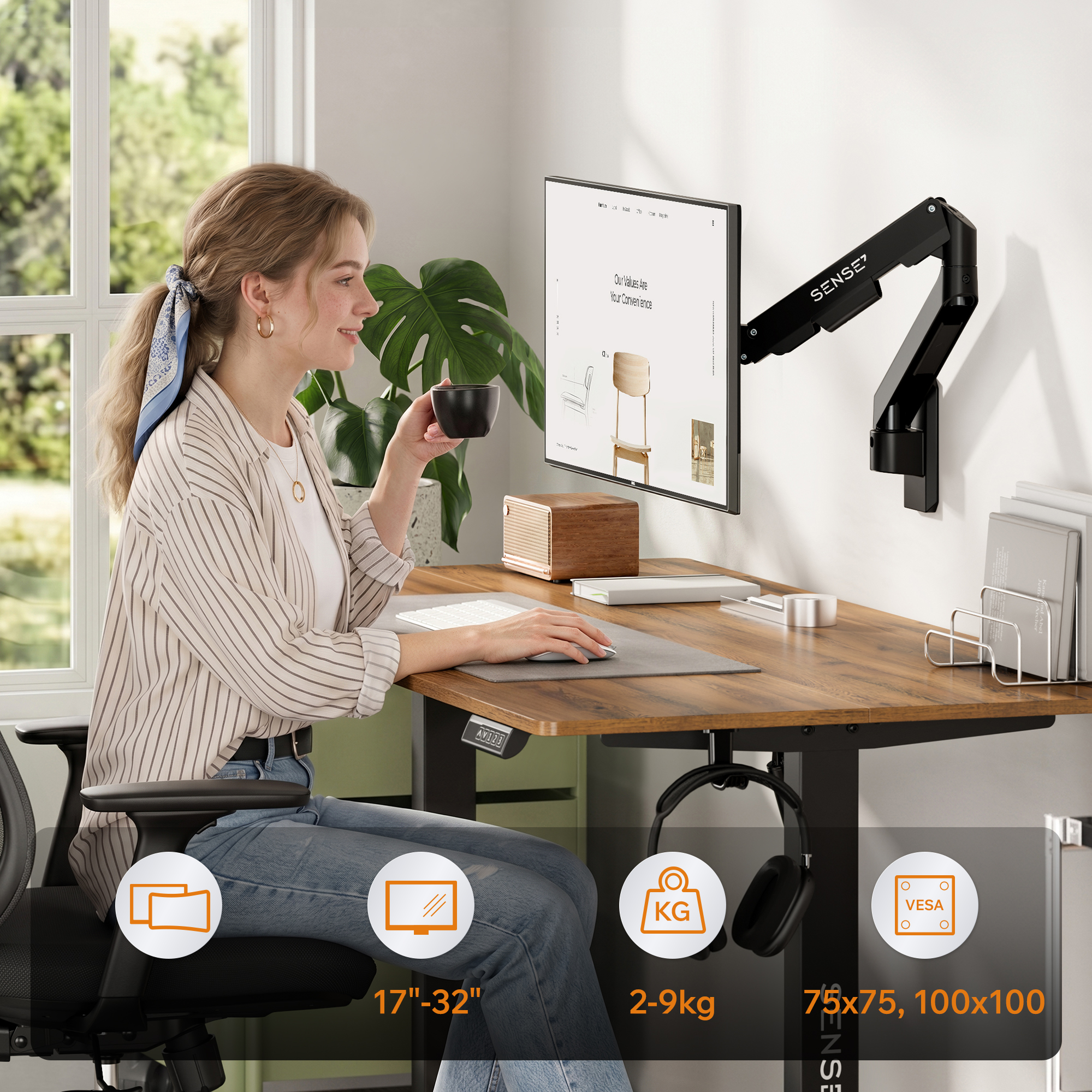 Eine Frau arbeitet an einem Holztisch mit einem Monitor, der an einem verstellbaren schwarzen Arm befestigt ist.