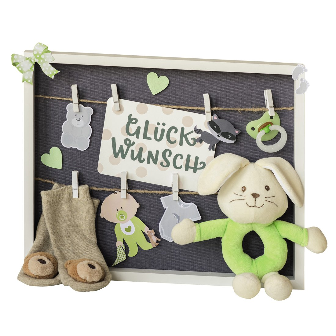 Ein weißer Holzrahmen mit dunkler Rückwand zeigt Babyartikel wie Socken, einen Schnuller und ein Plüschtier.