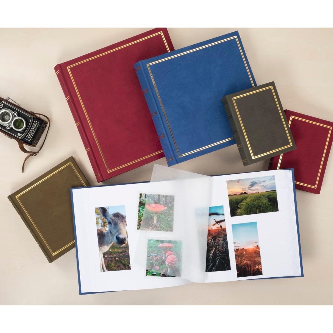 Varios álbumes de fotos coloridos, un álbum abierto con fotos de la naturaleza y una cámara retro en una mesa.