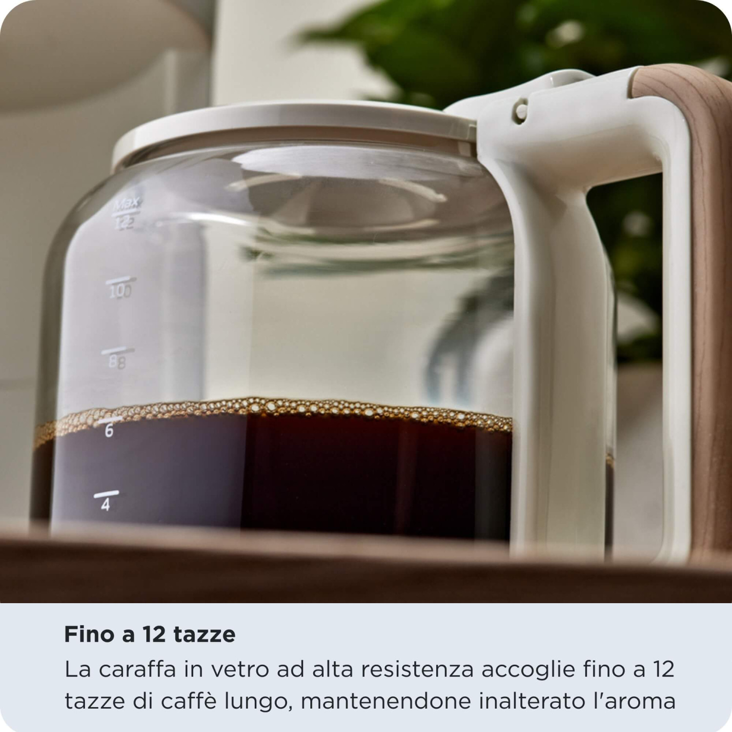 Caffettiera in vetro piena di caffè su un tavolo di legno con testo.